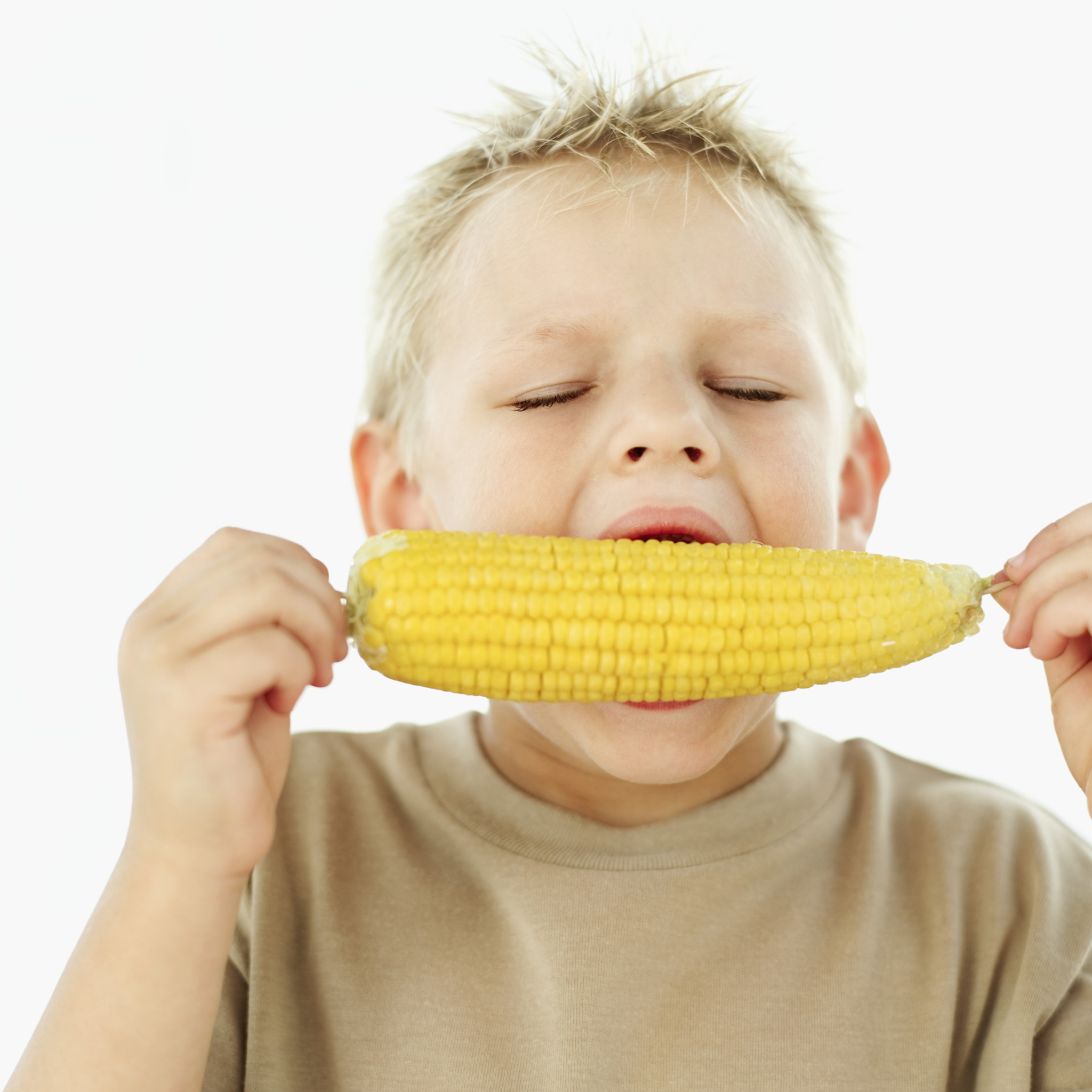 young boy (7-8) eating corn on the cob