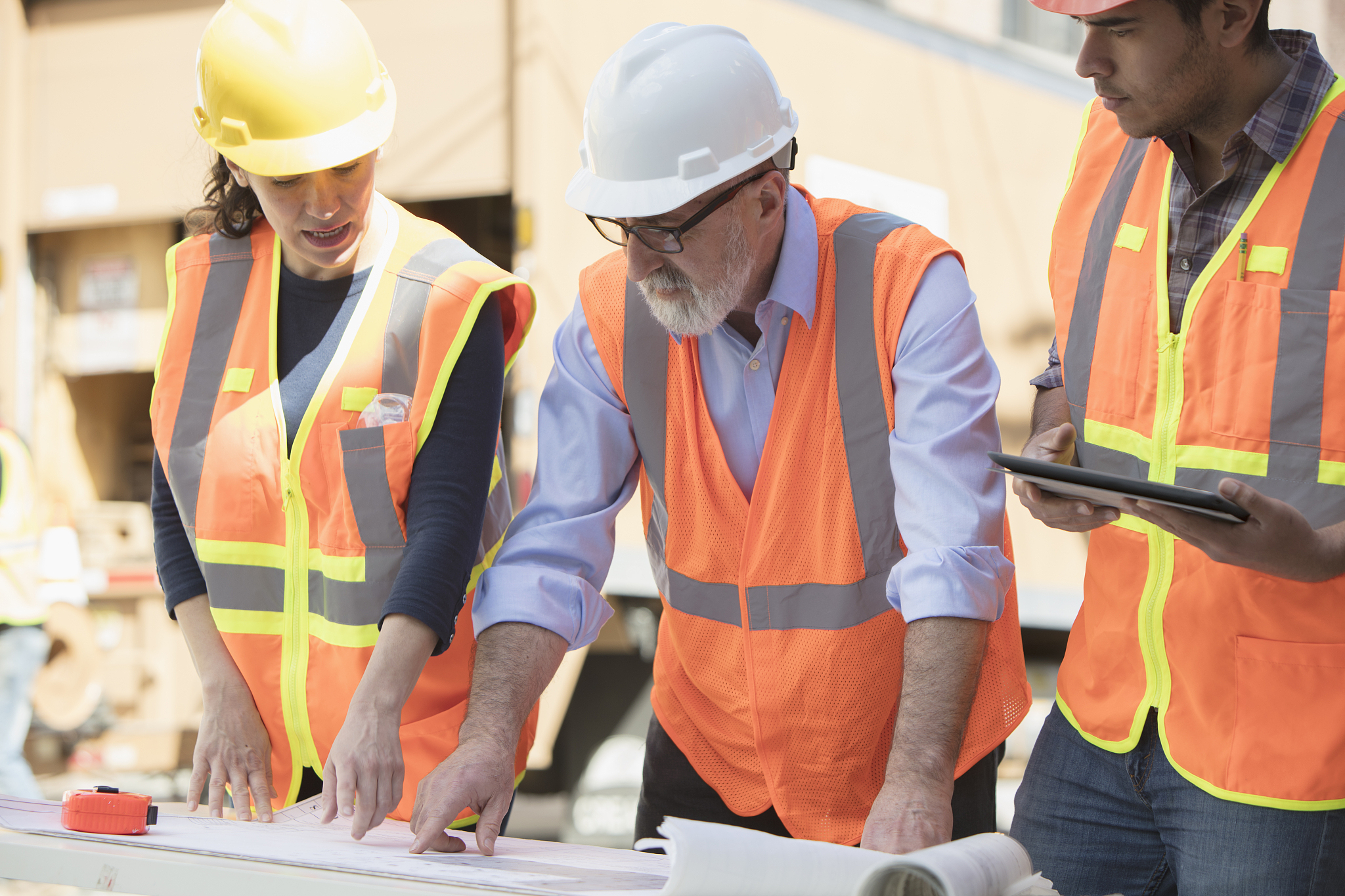 confident architect explaining blueprint to workers