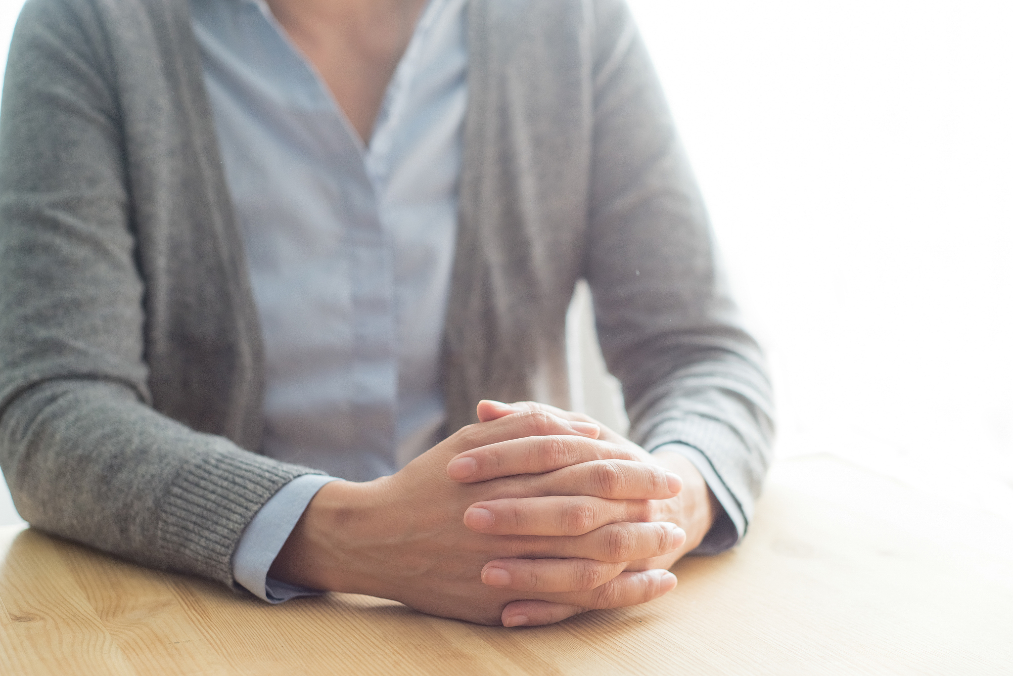 closeup of woman at table with clasped hands