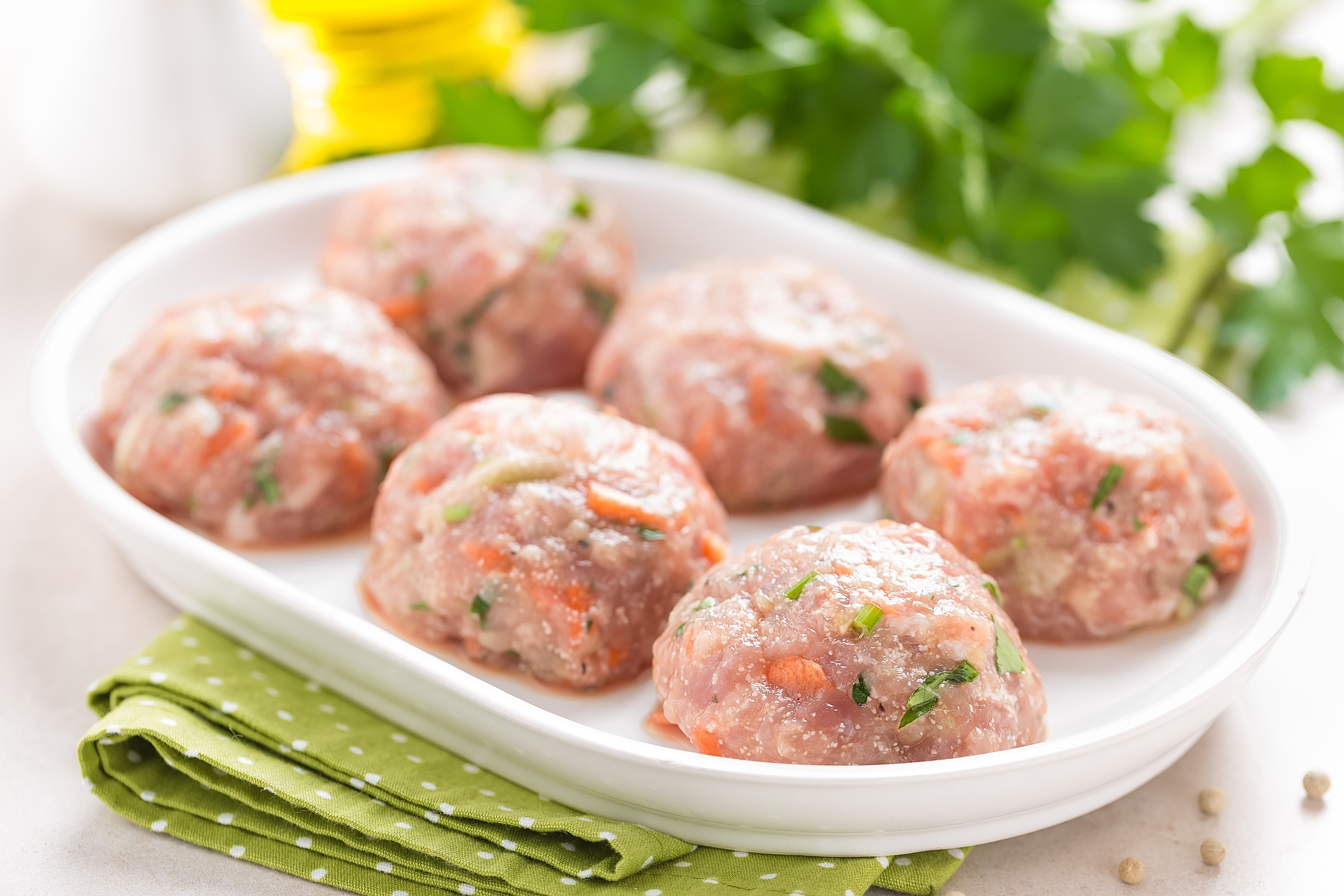 raw meatballs on white plate, cooking in kitchen