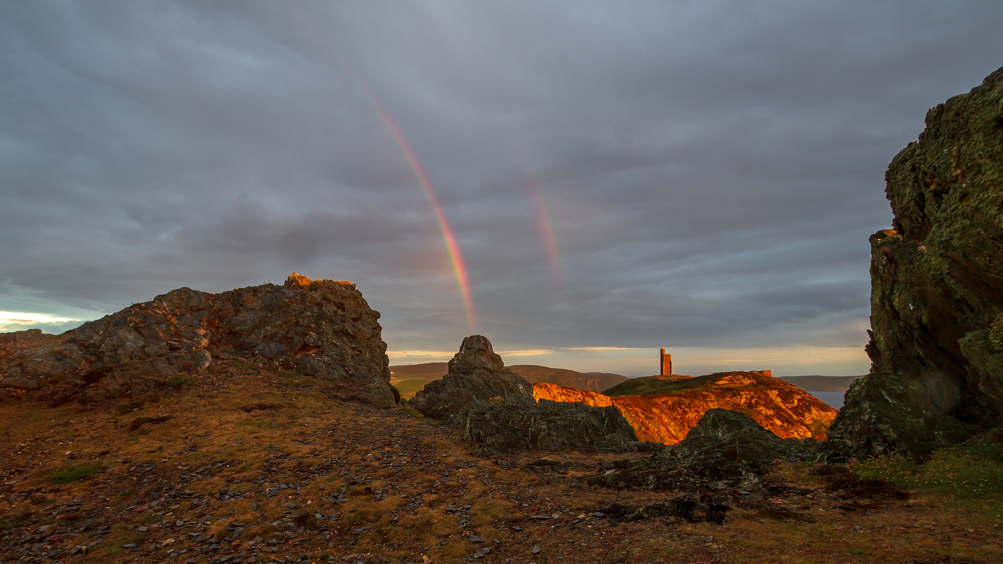 scenic view of rainbow over landscape against sky