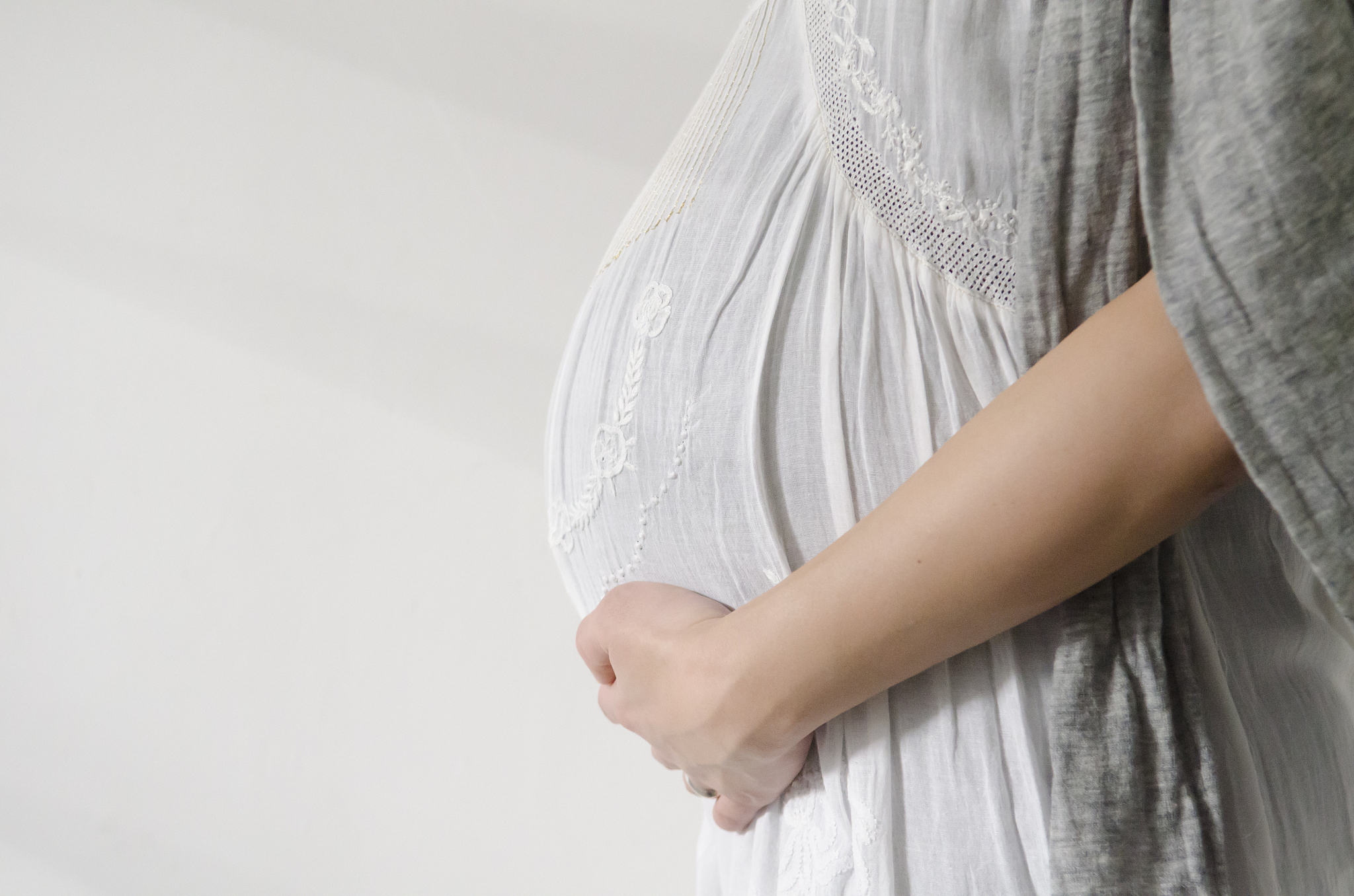 side view of a pregnant woman in room,holding her abdomen