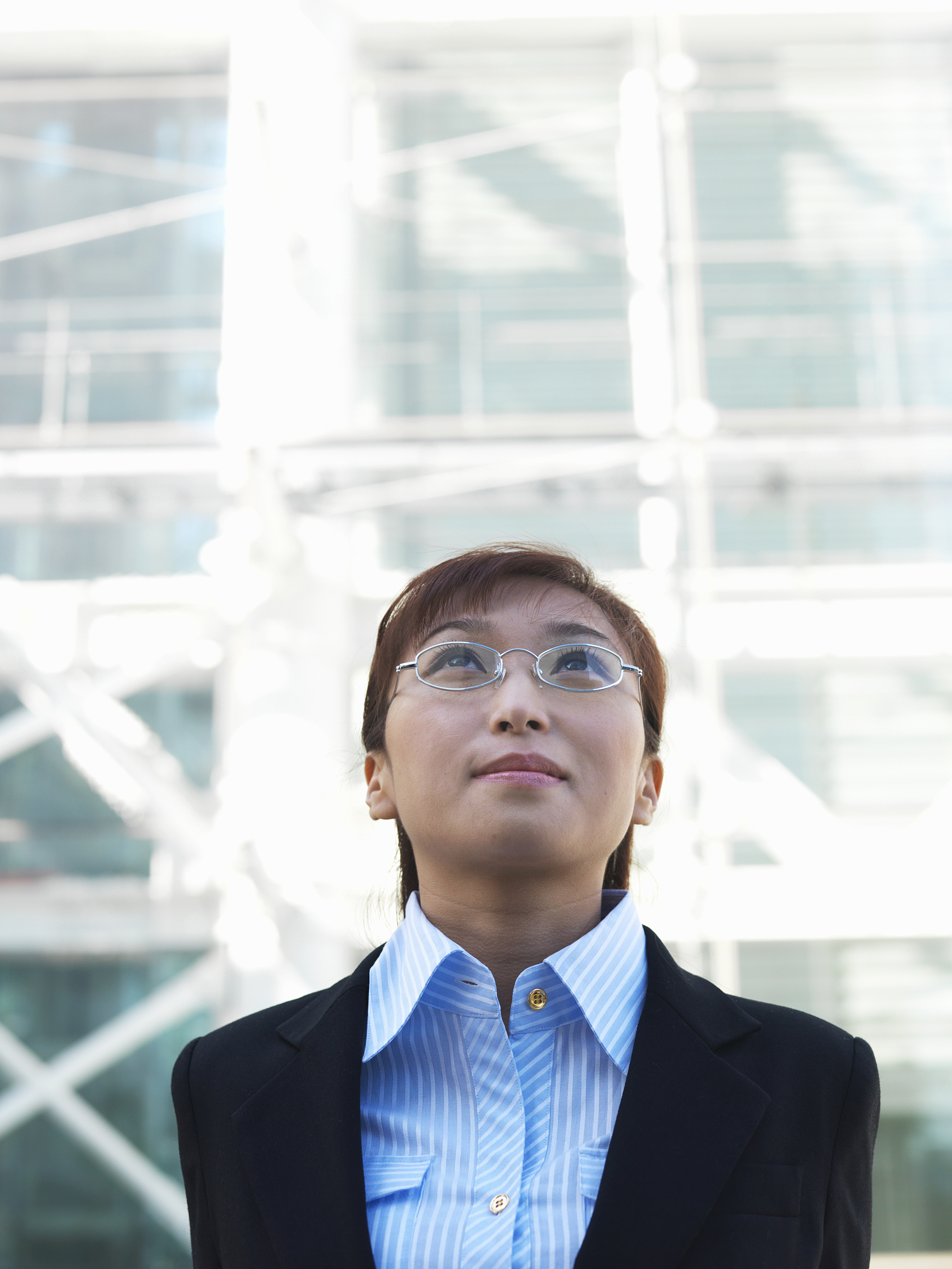 young businesswoman standing outdoors, looking up