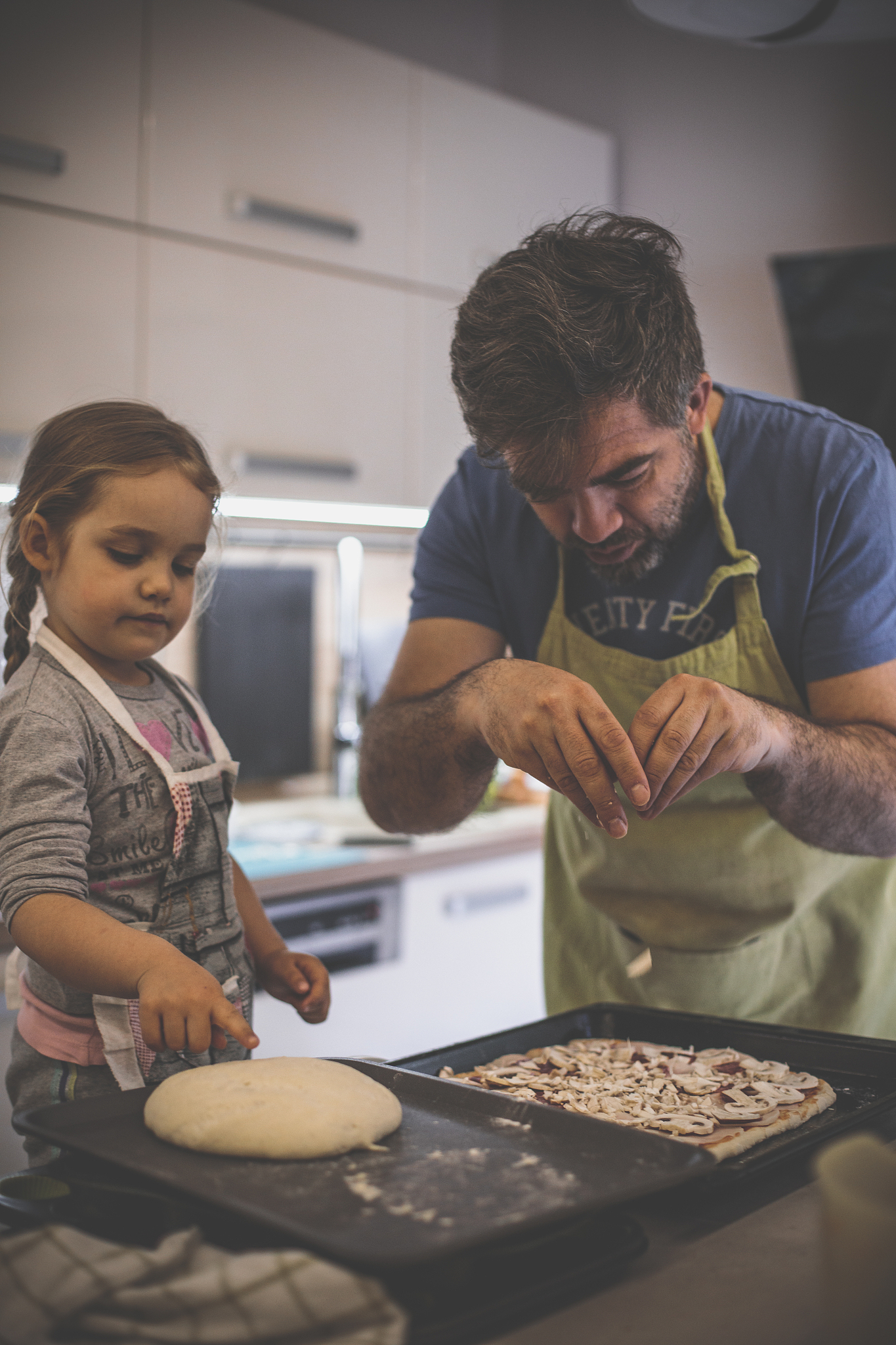 adding the last ingredients for a family pizza
