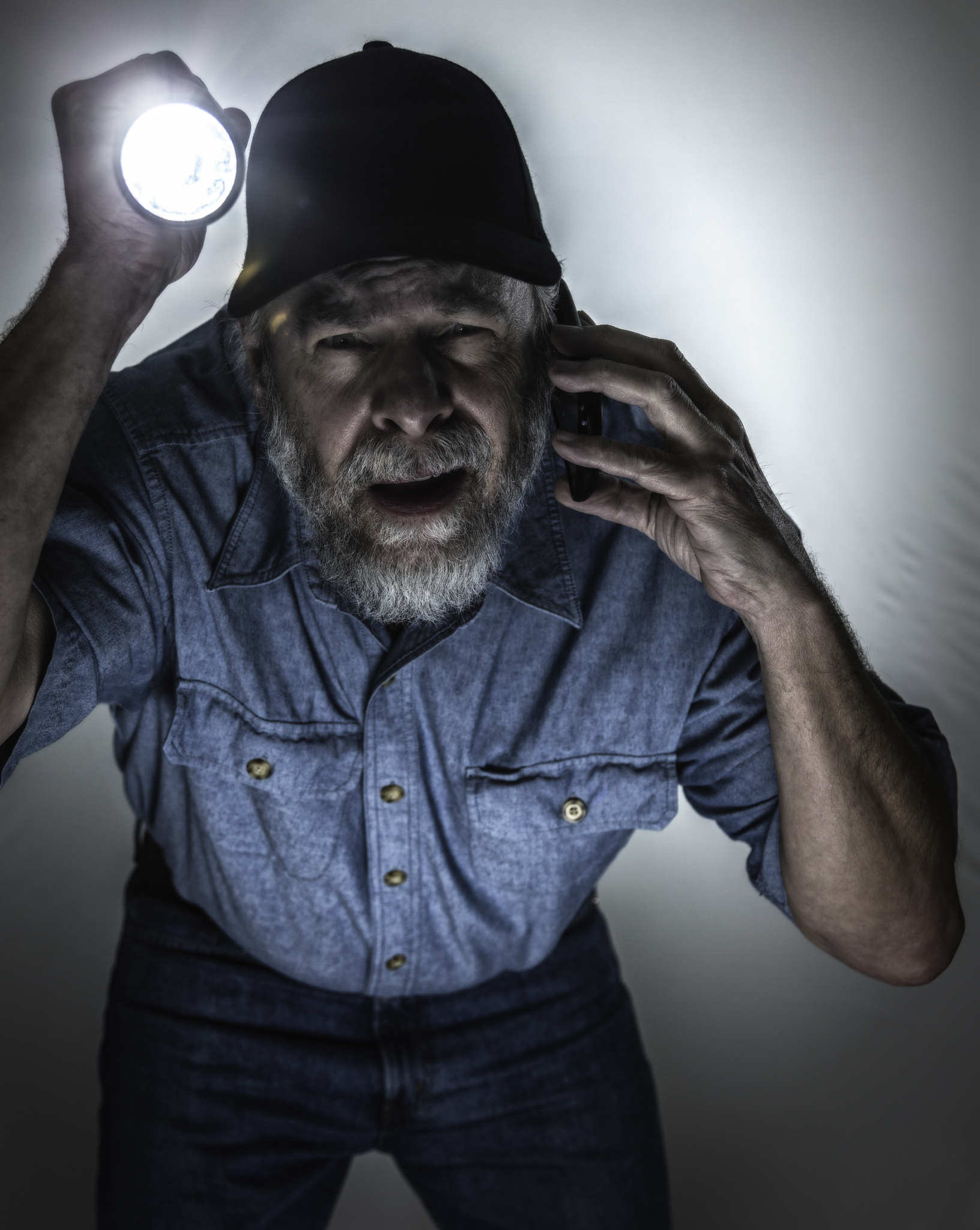 repairman talking on cellphone aiming flashlight in dark room