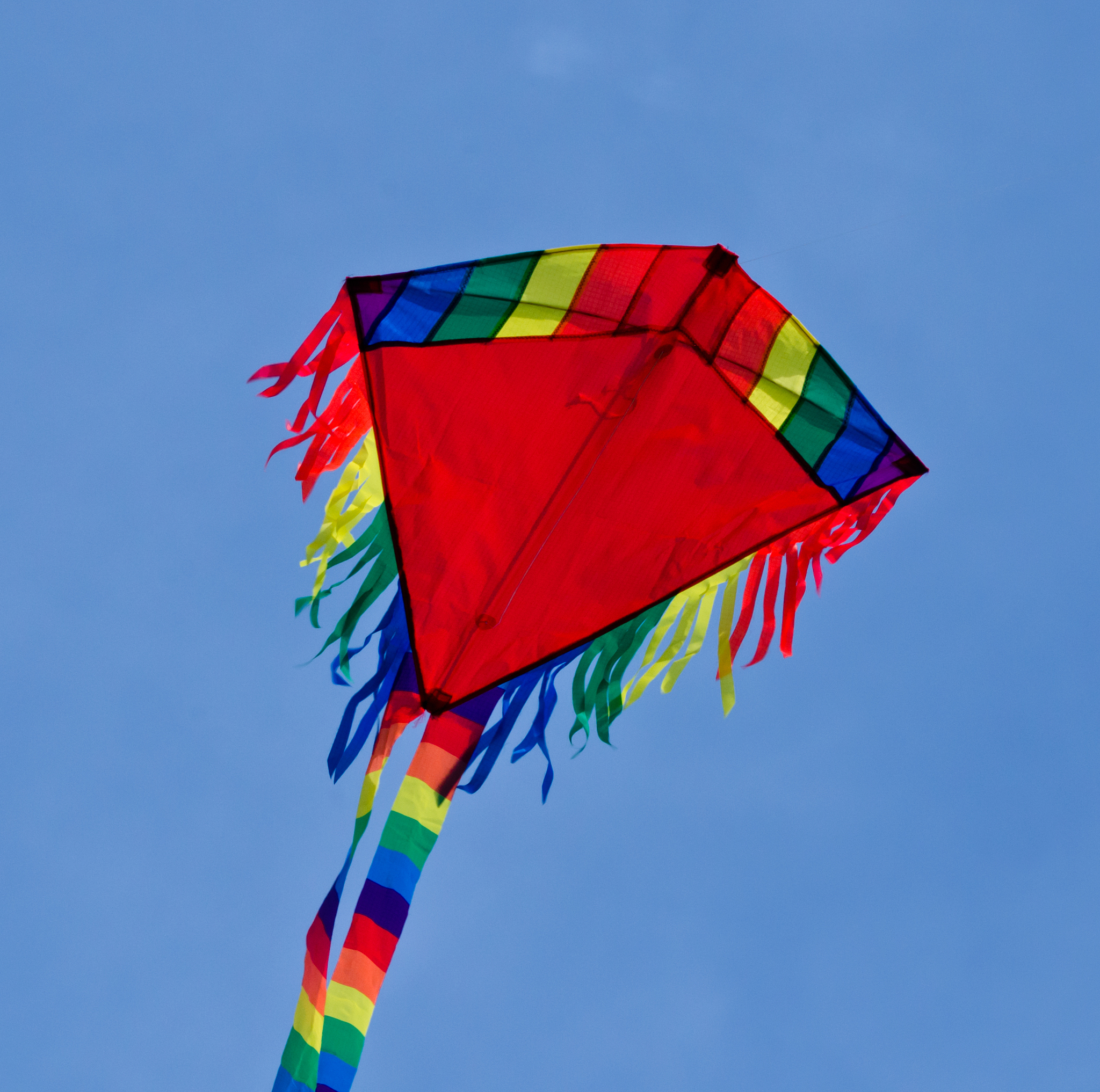 a beautiful, colourful stunt kite, in the blue sky, high up in t