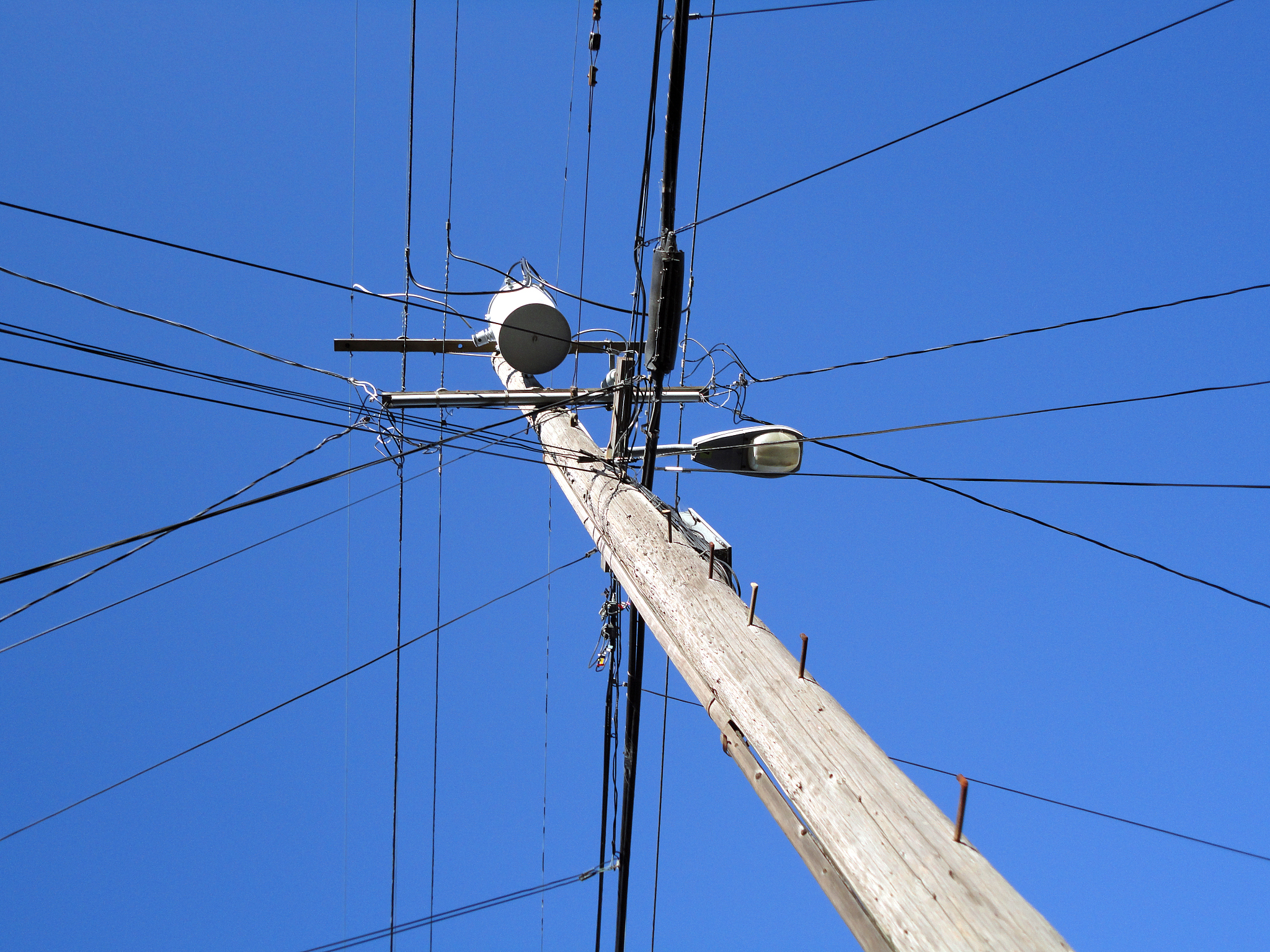 high voltage power lines intersect at a wooden utility