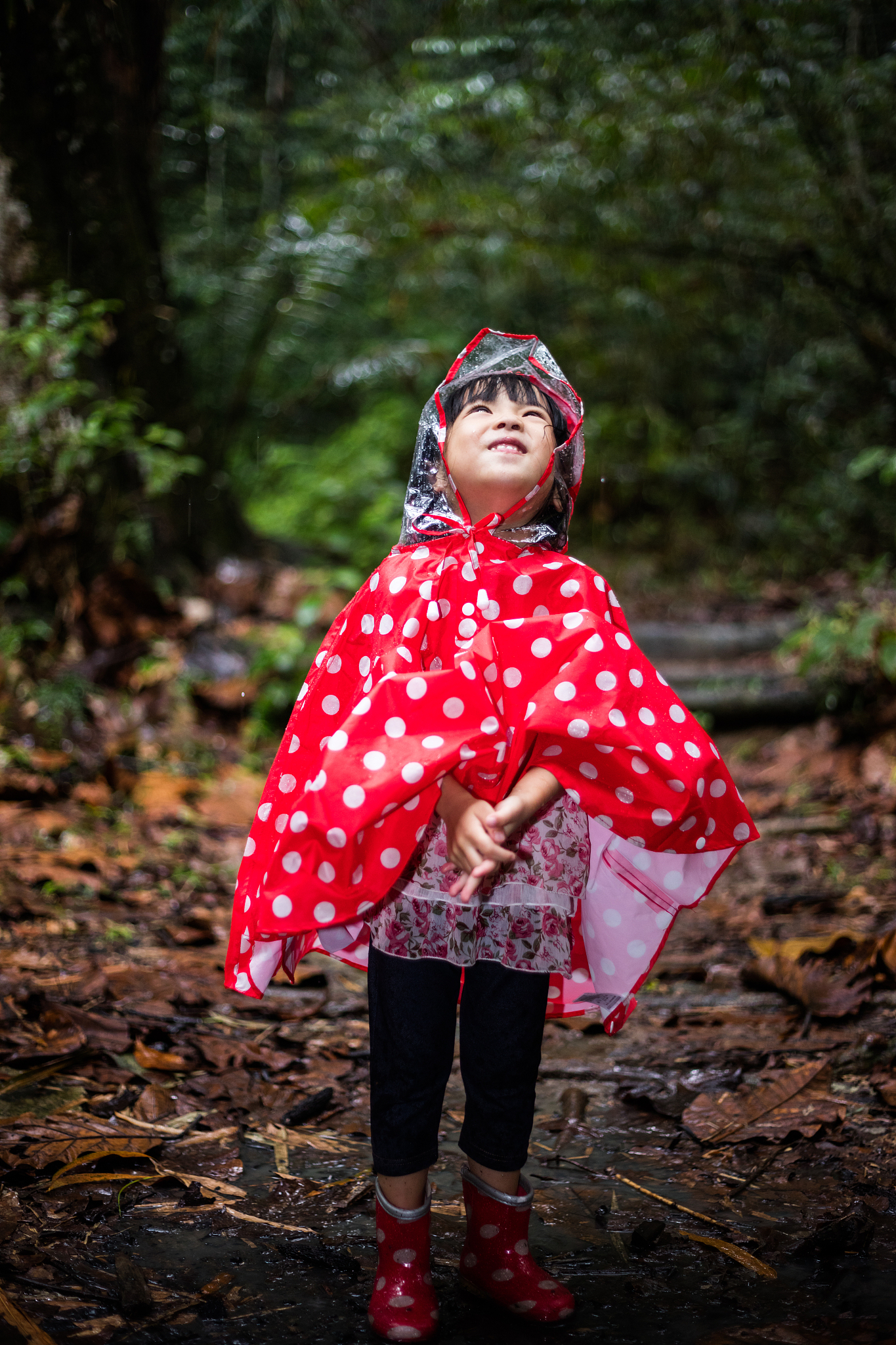 happy asian chinese little girl wearing raincoat in forest