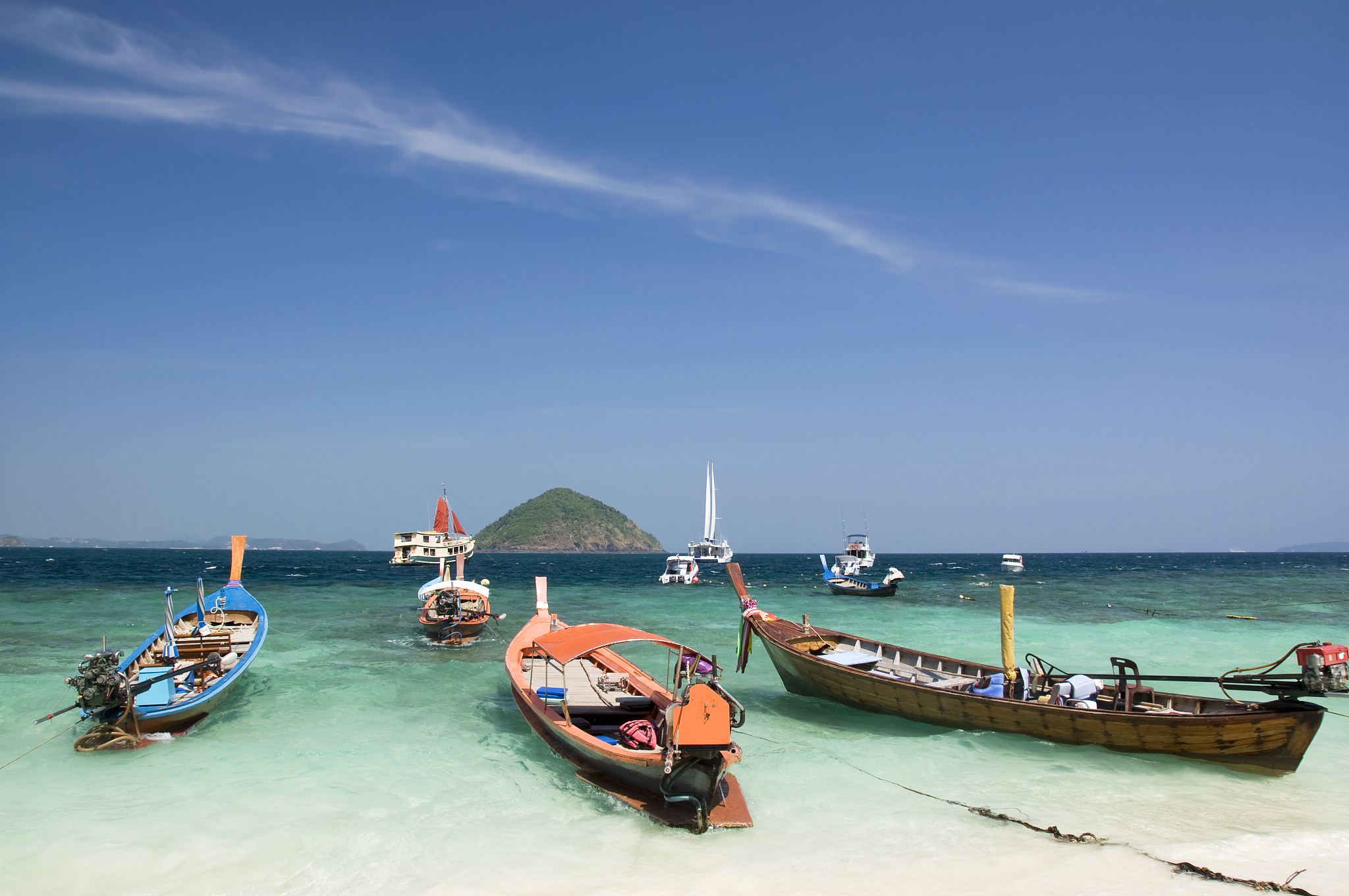 multiple longtail boats at the beach