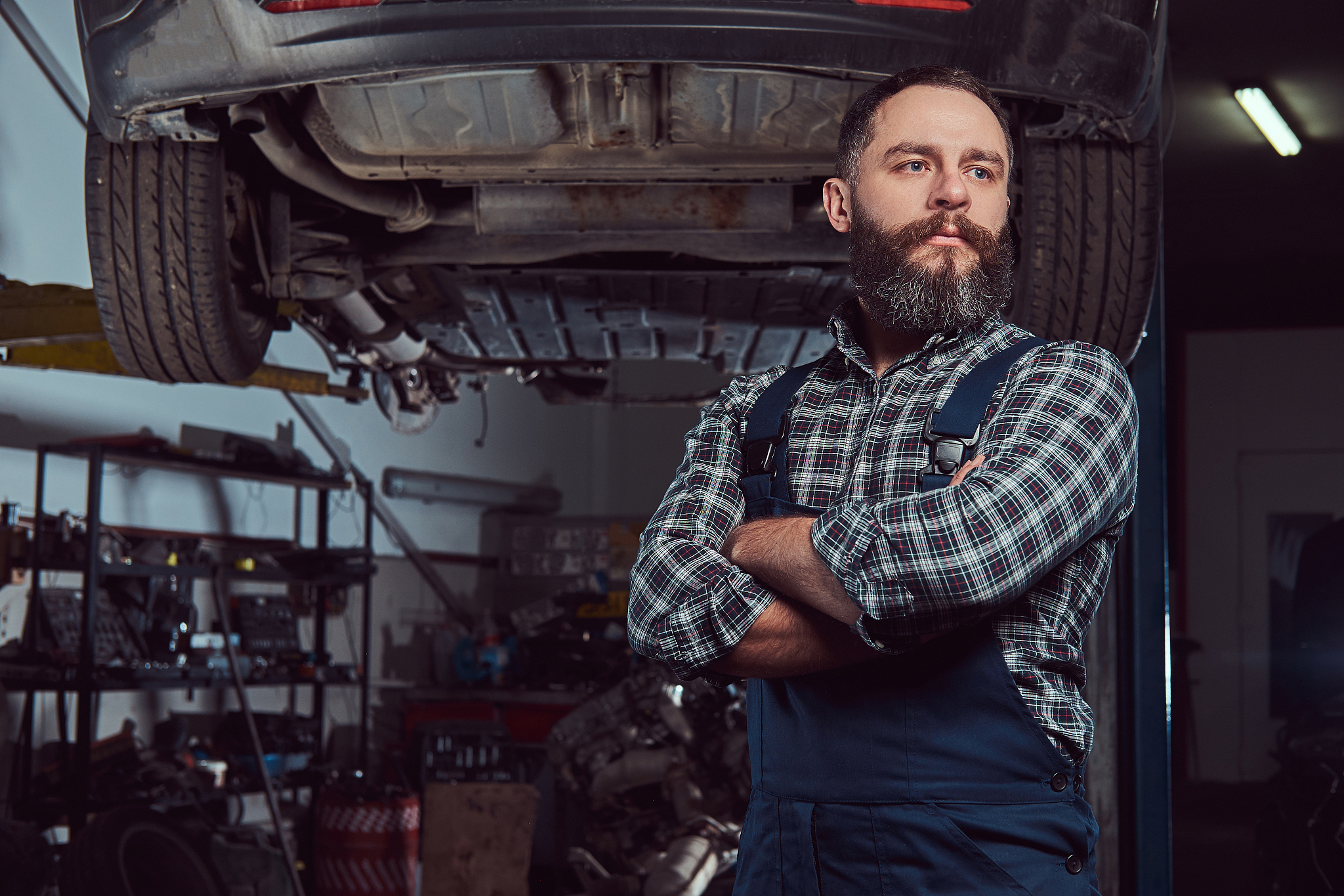 two bearded brutal mechanics repair a car on a lift in the garag