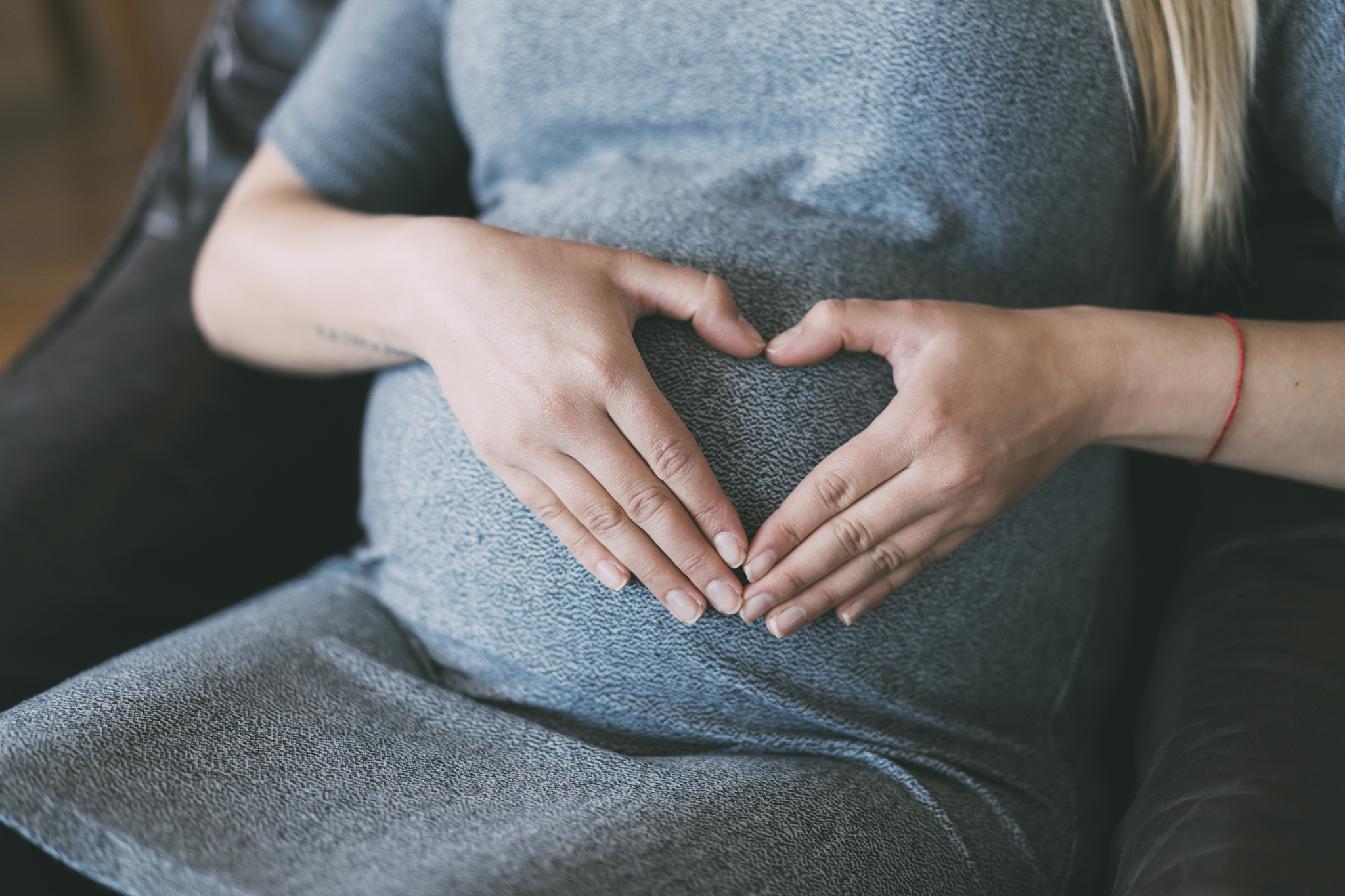 pregnant woman making heart shape with hands on her belly