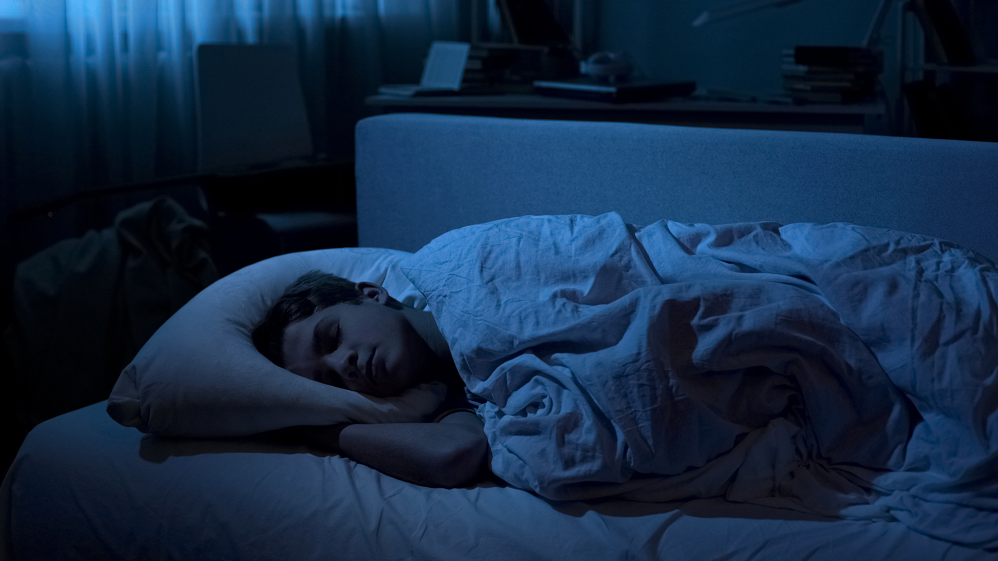nice young boy sleeping deep in his bed after hard day at univer