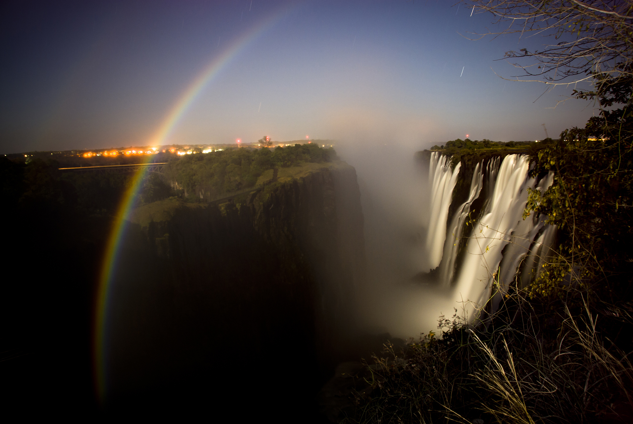 night scene of moon rainbow over deep gorge with waterfall on ri