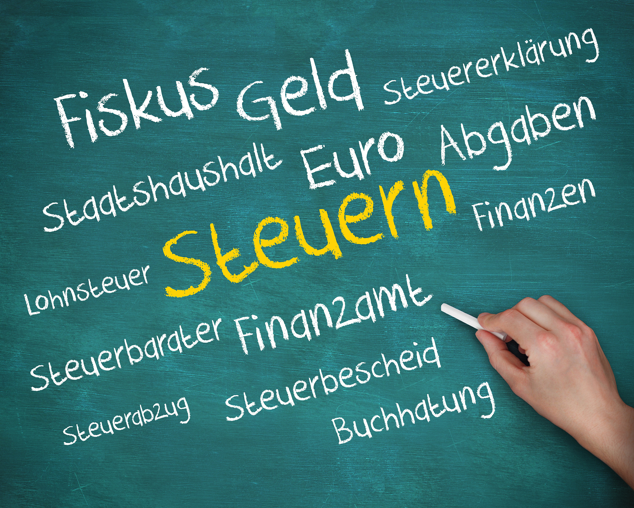 hand holding a chalk and writing several words about tax in germ