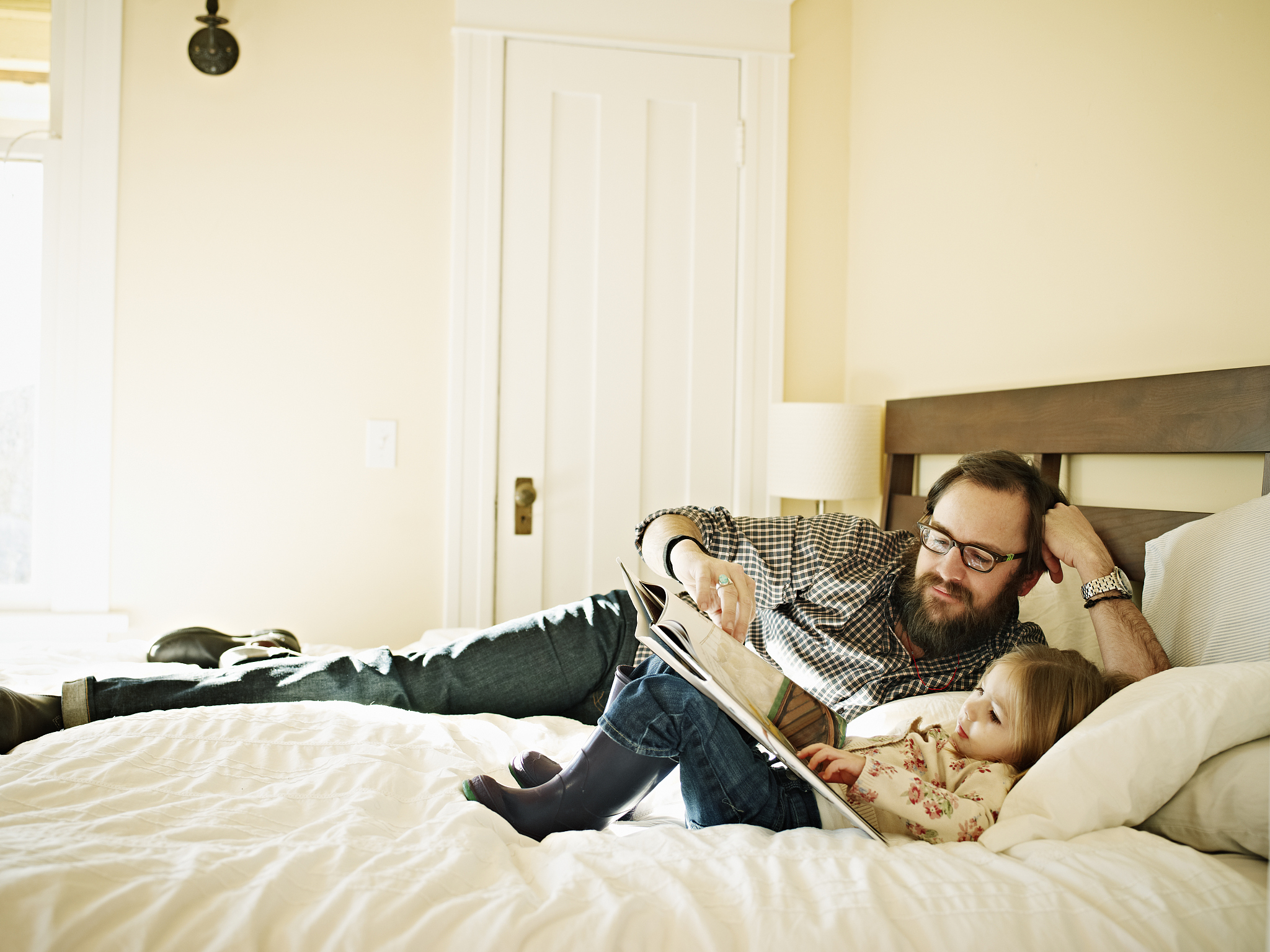 father and daughter reading book in bed