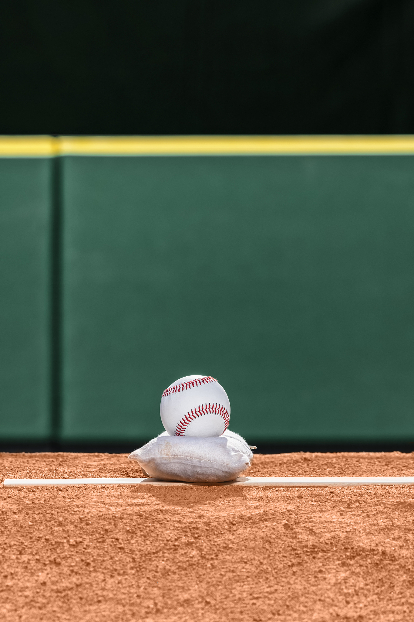 a new baseball sitting atop a rosin bag on pitcher's mound