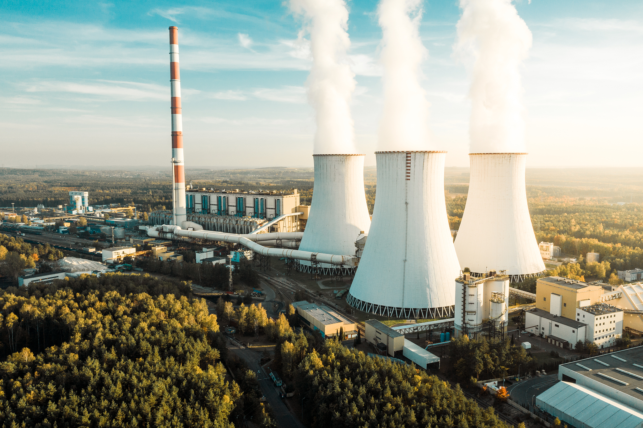 a power plant with white smoke over it's chimneys