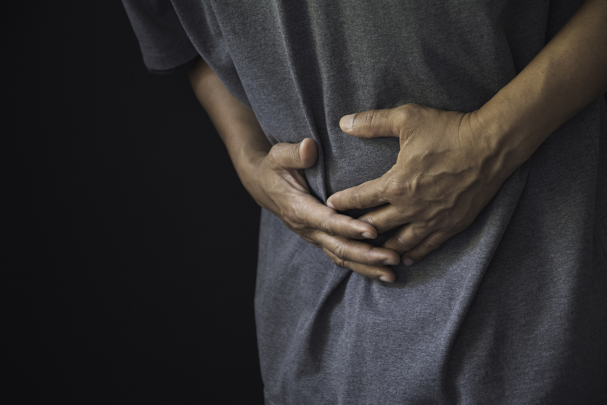 midsection of man with stomachache against black background