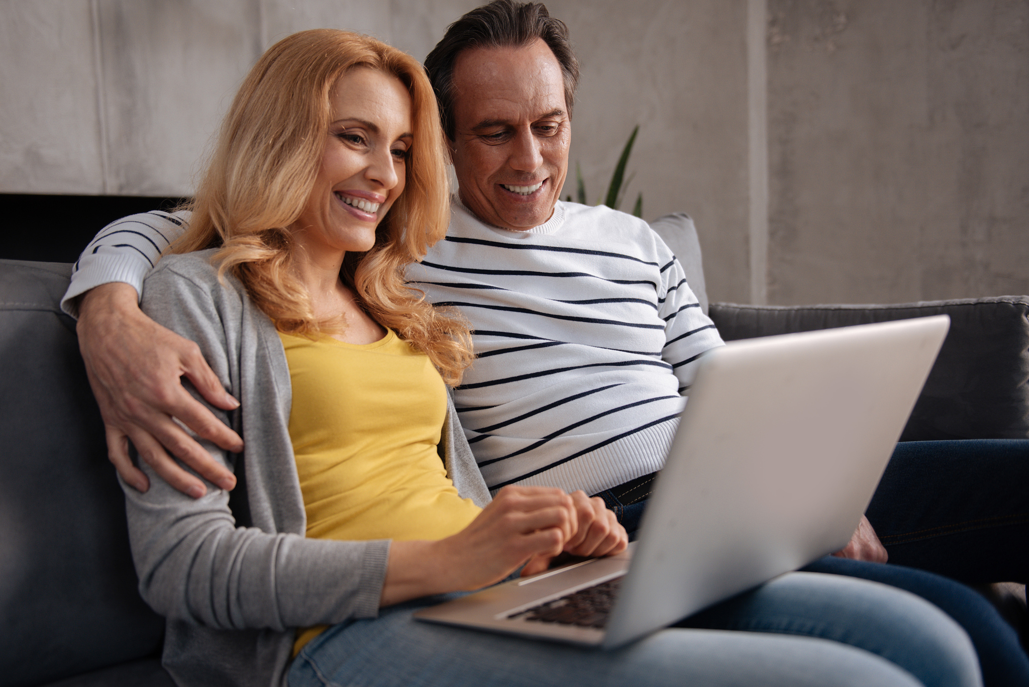 delighted mature couple enjoying new electronic gadget at home