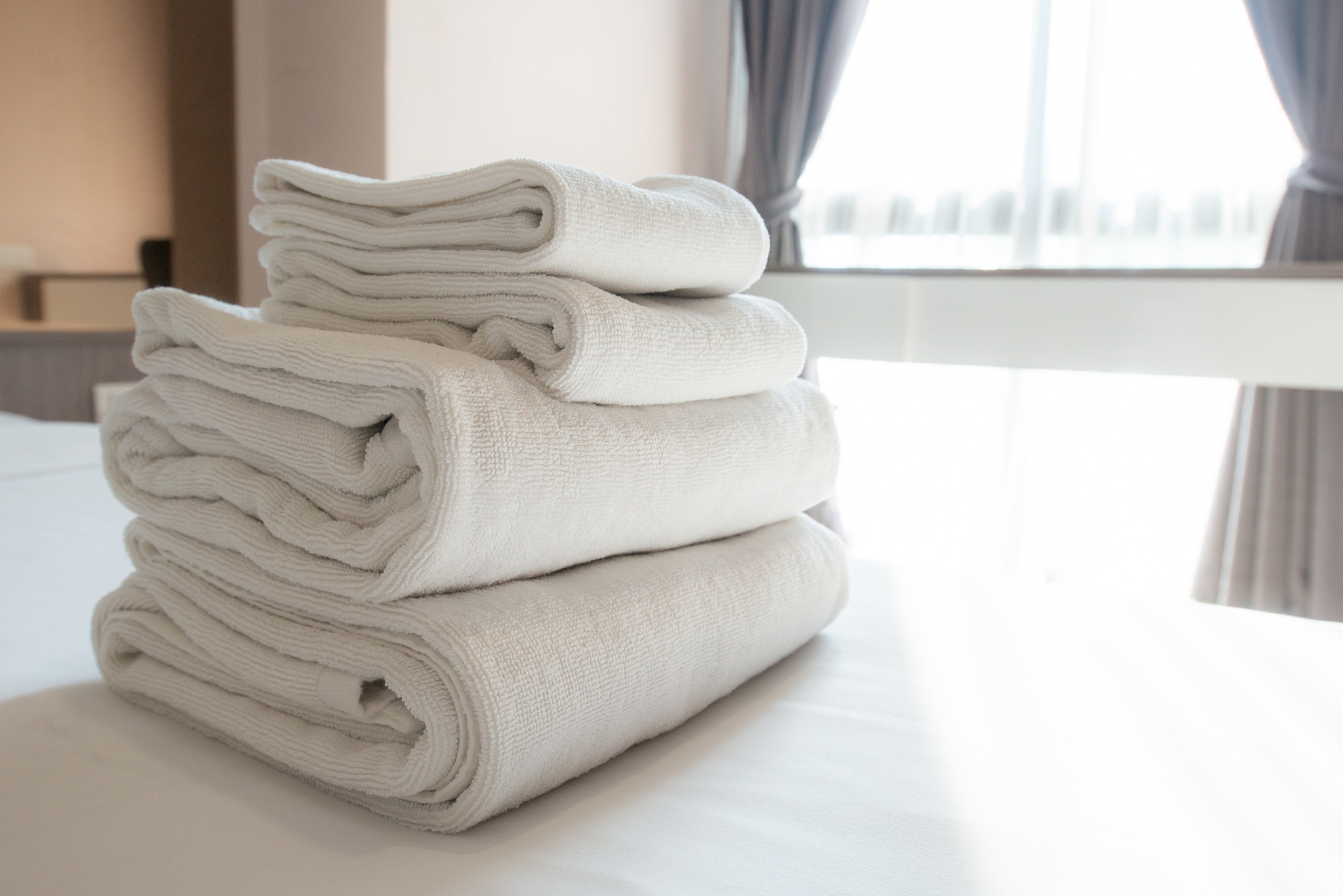stack of soft towel on the bed in comfortable hotel bedroom.