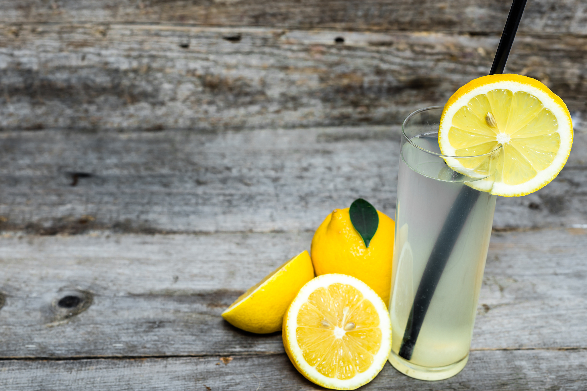 glass of lemon drink - cold lemonade on wooden table