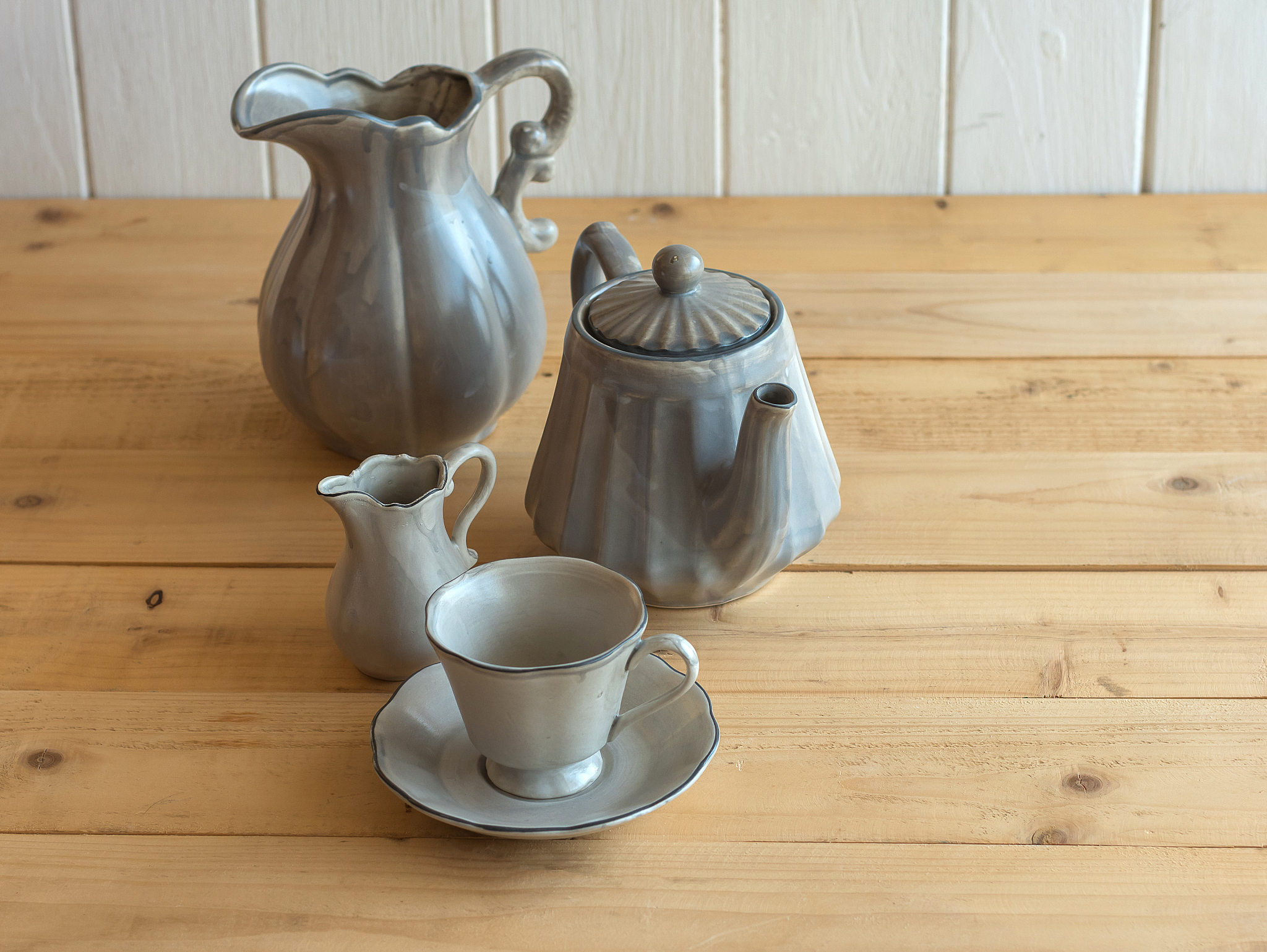 tea set is gray on a wooden background. teapot, creamer, cup and