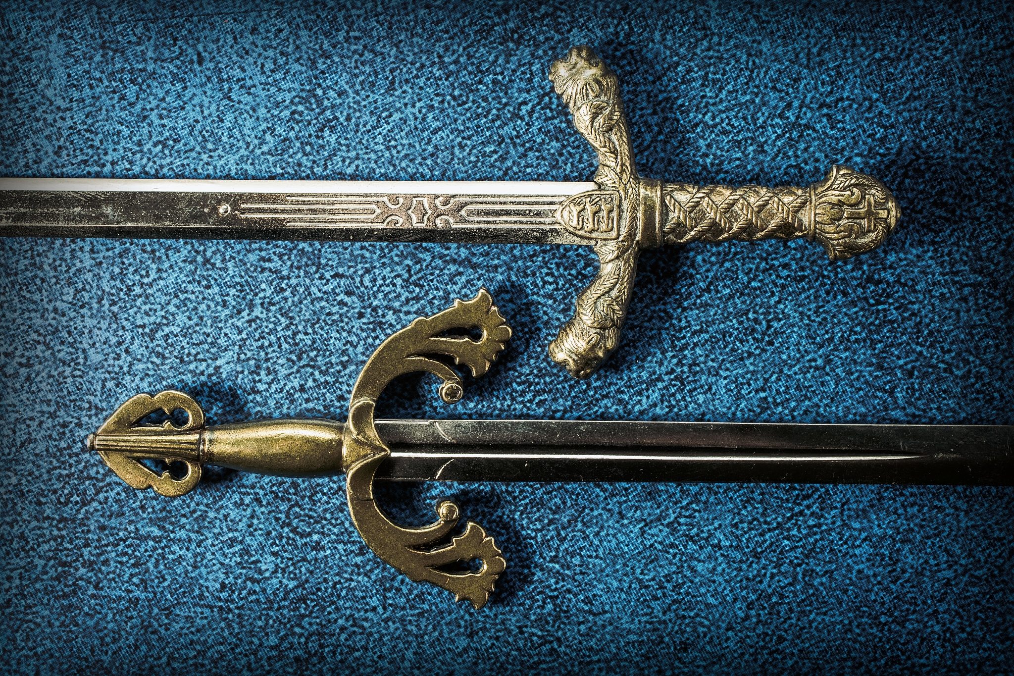 two hilt of knightly swords close-up on a dark blue background. 