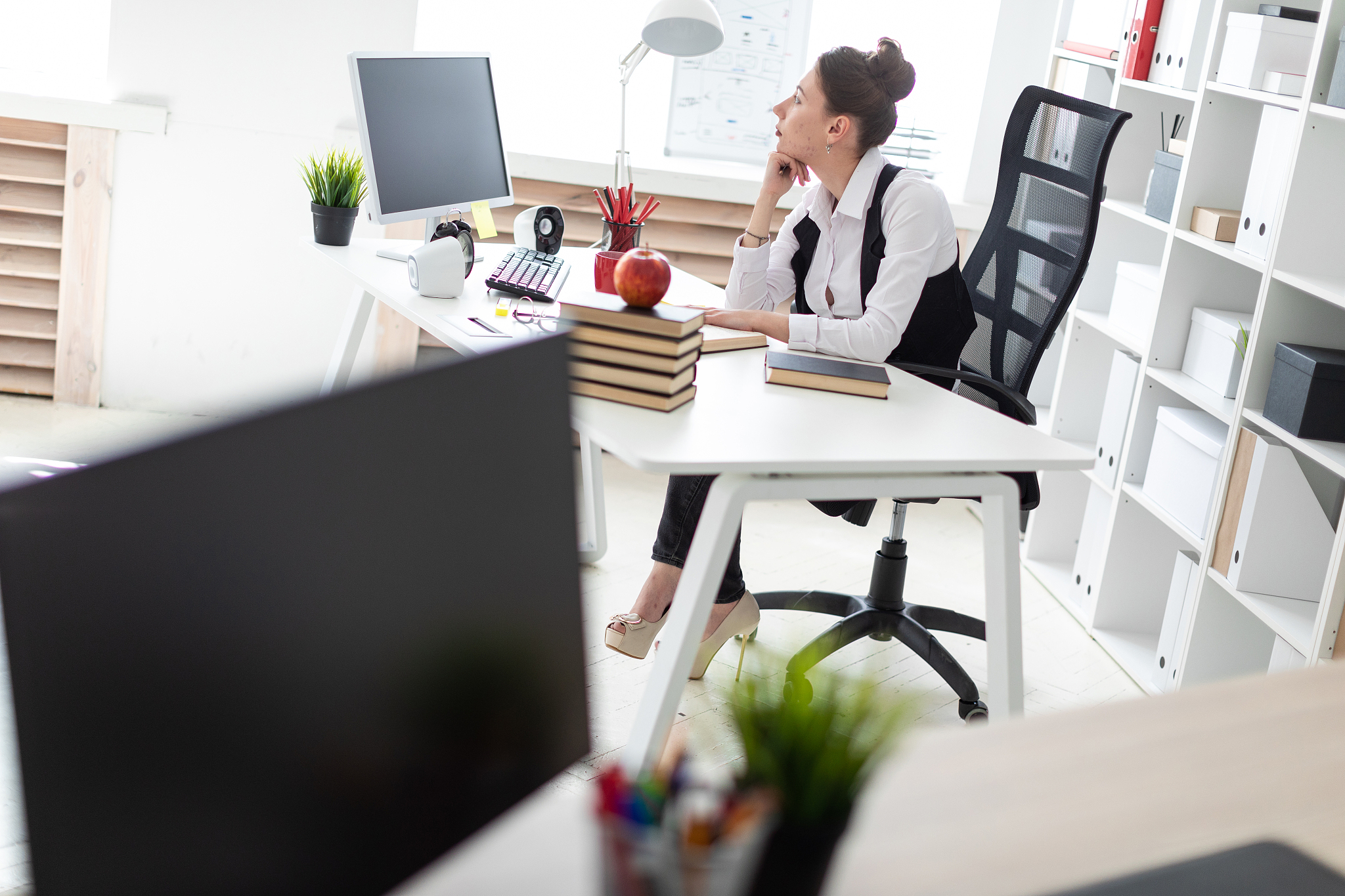 a young girl is sitting at the computer desk in the office.