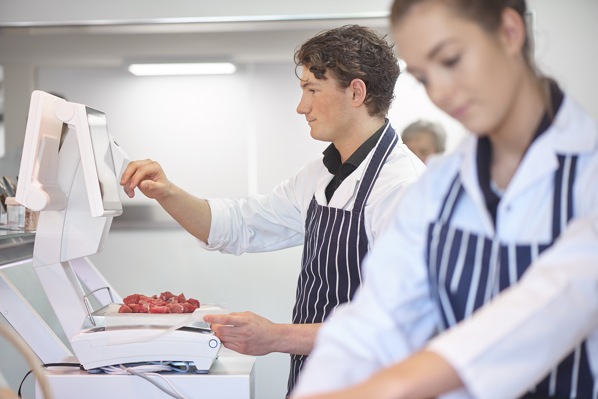 young male and female butchers working in a butcher's shop.