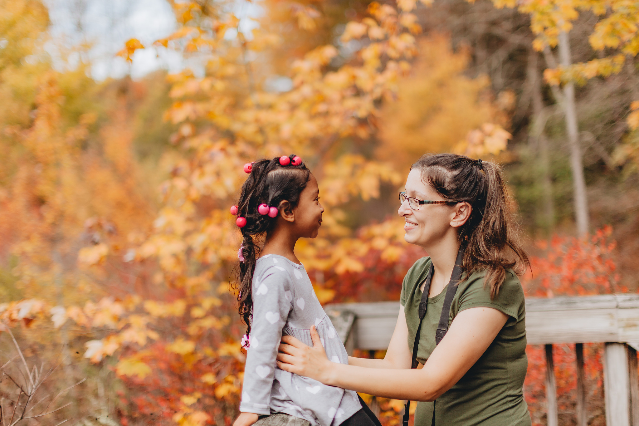 smiling mother embracing daughter while sitting at park during a