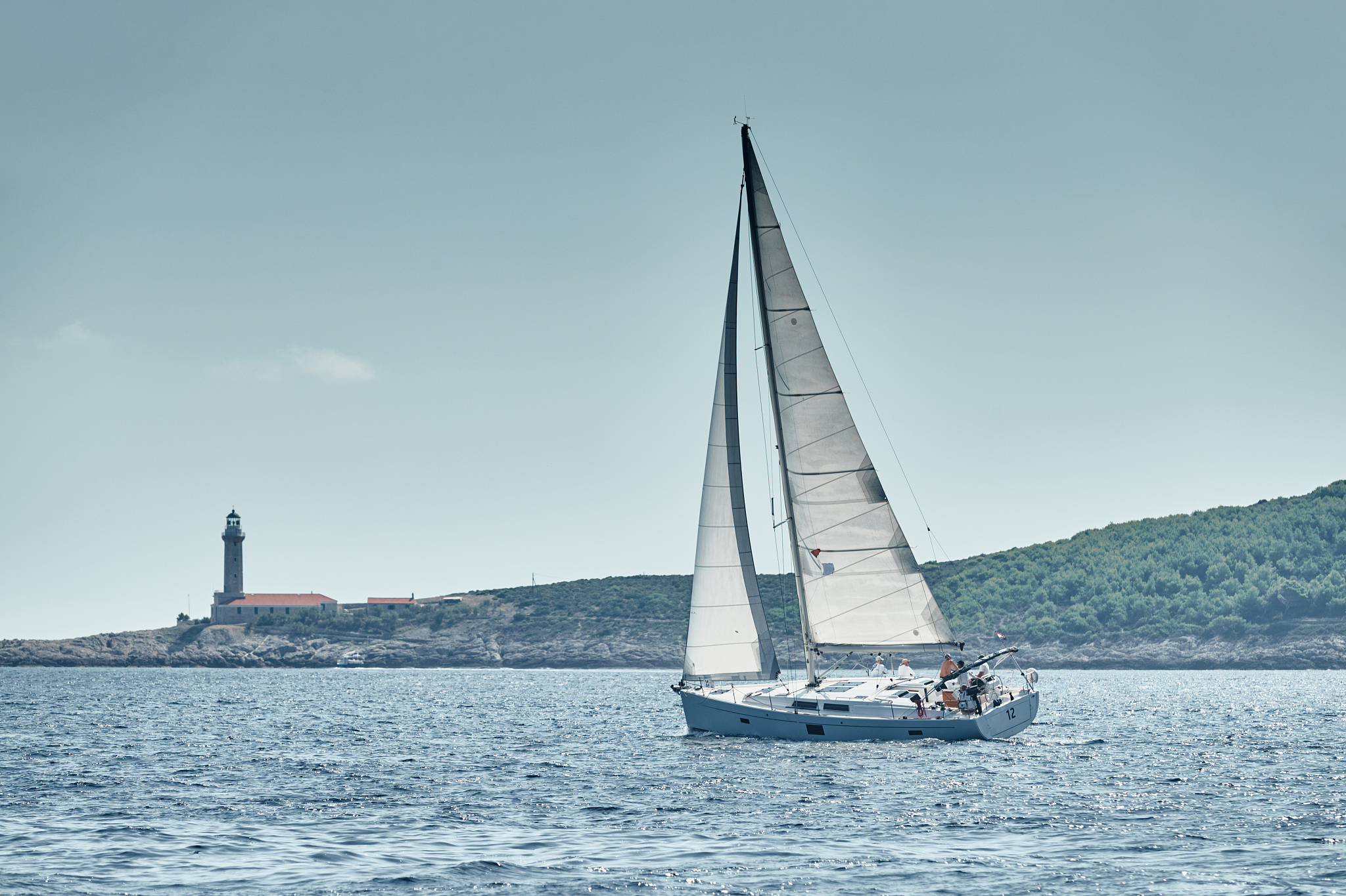 seascape of the sailboat in the foreground, the lighthouse on th