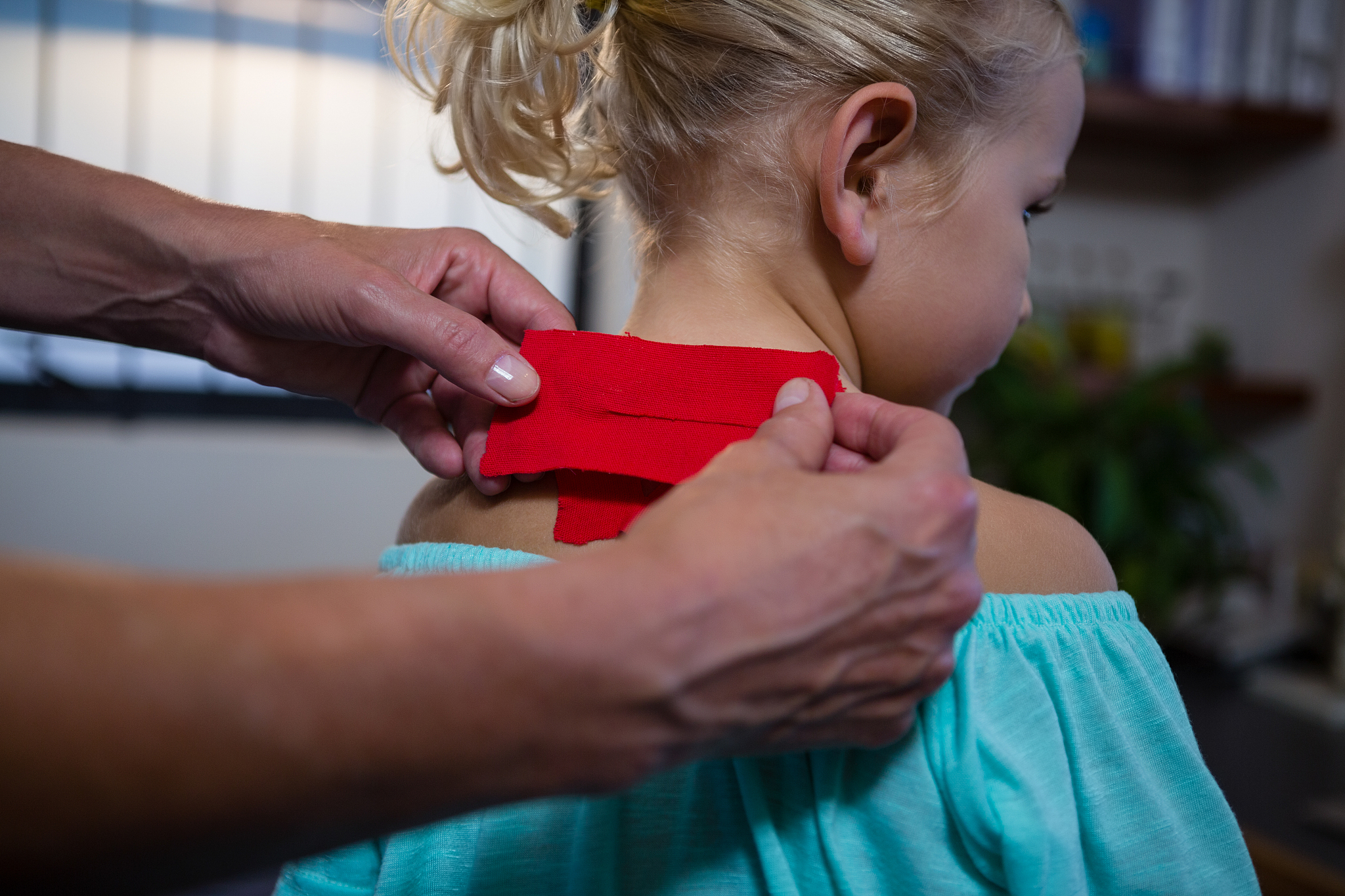 physiotherapist sticking tape on girl patient in hospital