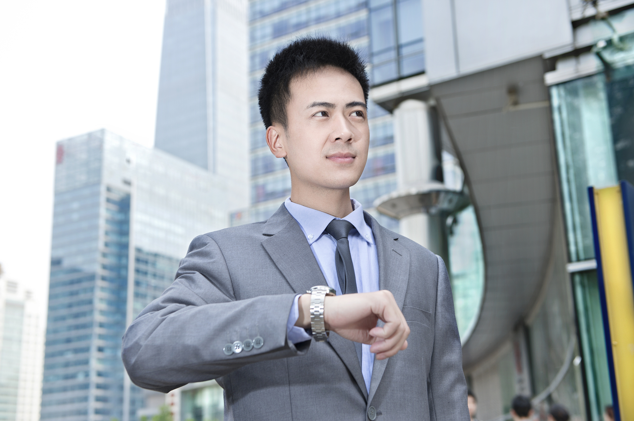 站在大楼前看时间的商务男士
