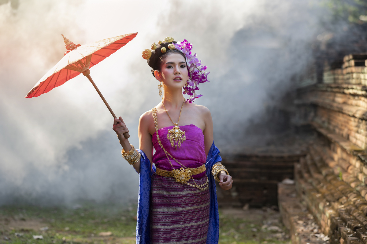 身着泰国传统服饰的泰国美女,手持红伞,置身于烟雾之
