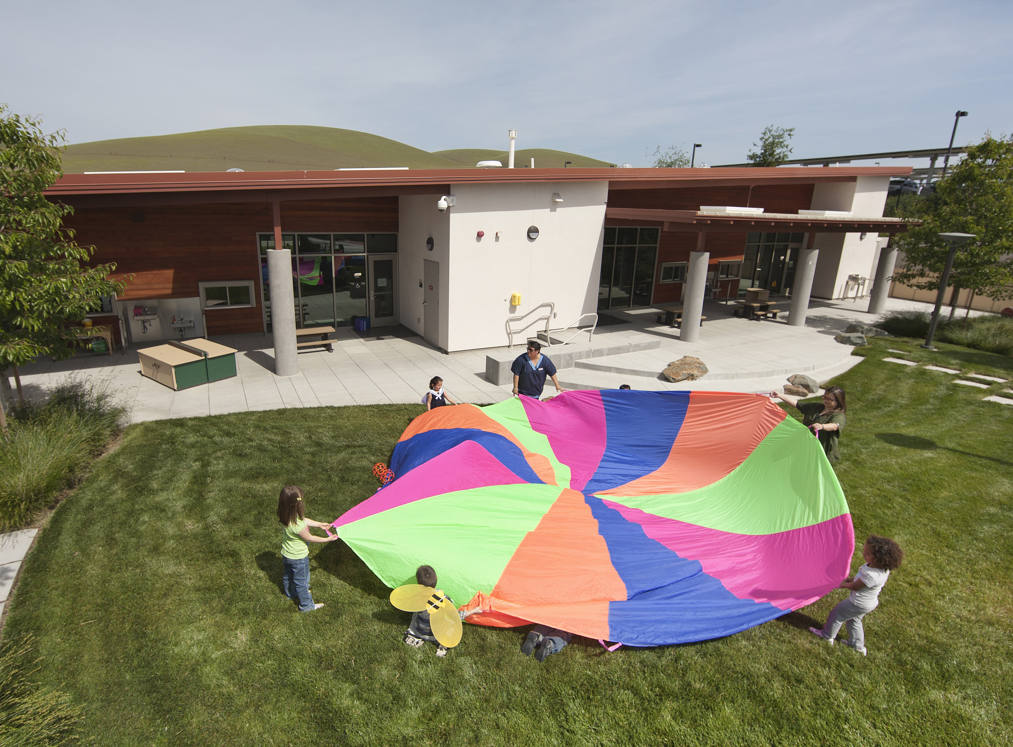 teacher and students holding a colorful parachute