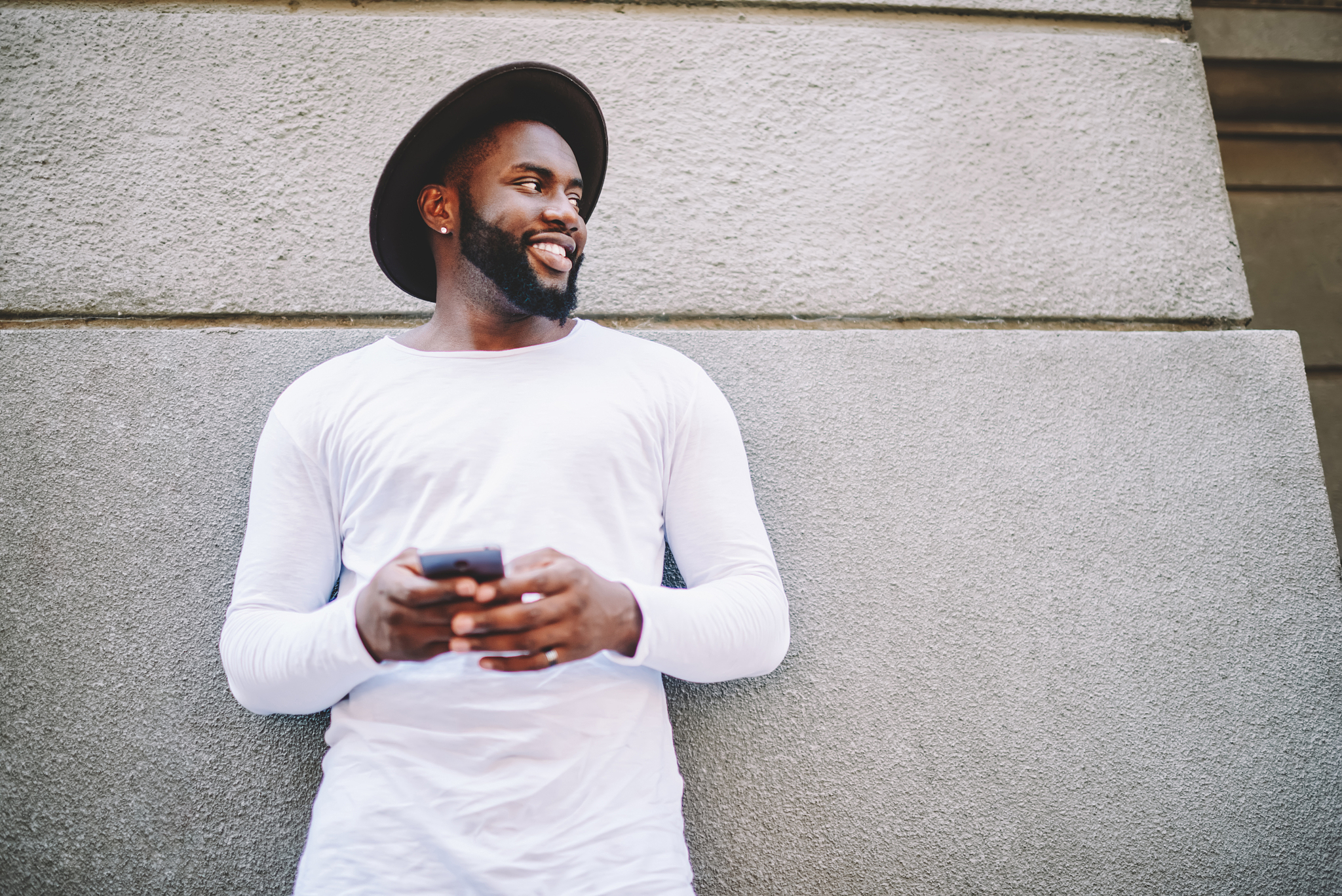 handsome african american guy in trendy hat chatting via smartph