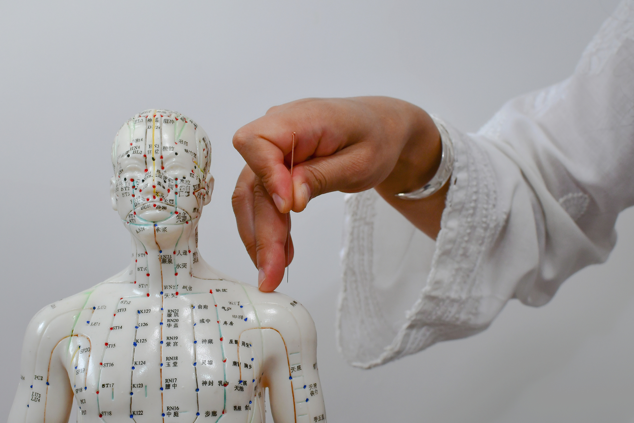 cropped hand of doctor giving acupuncture to dummy