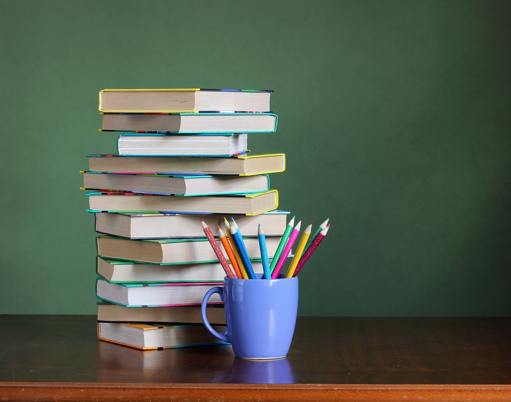 stack of books and colored pencils on the table. back to school.