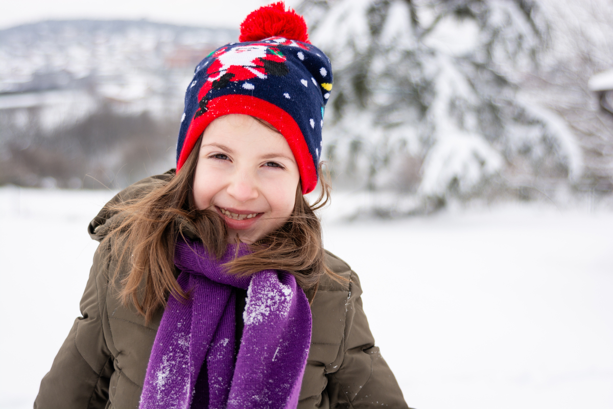 快乐的小学女生在冬天的雪景中微笑