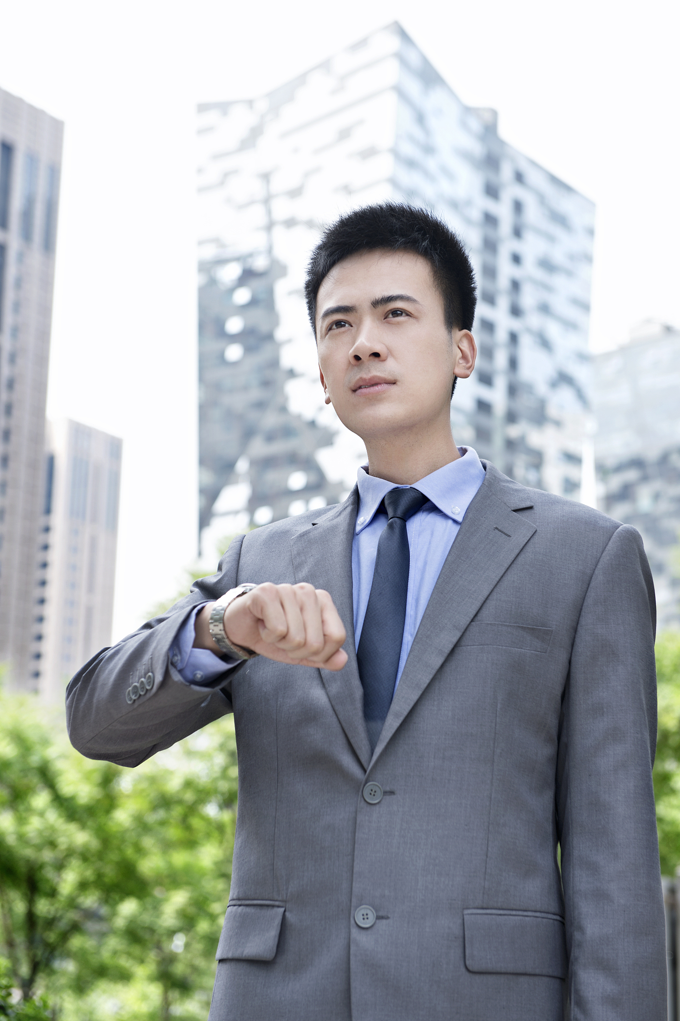 站在大楼前看时间的商务男士