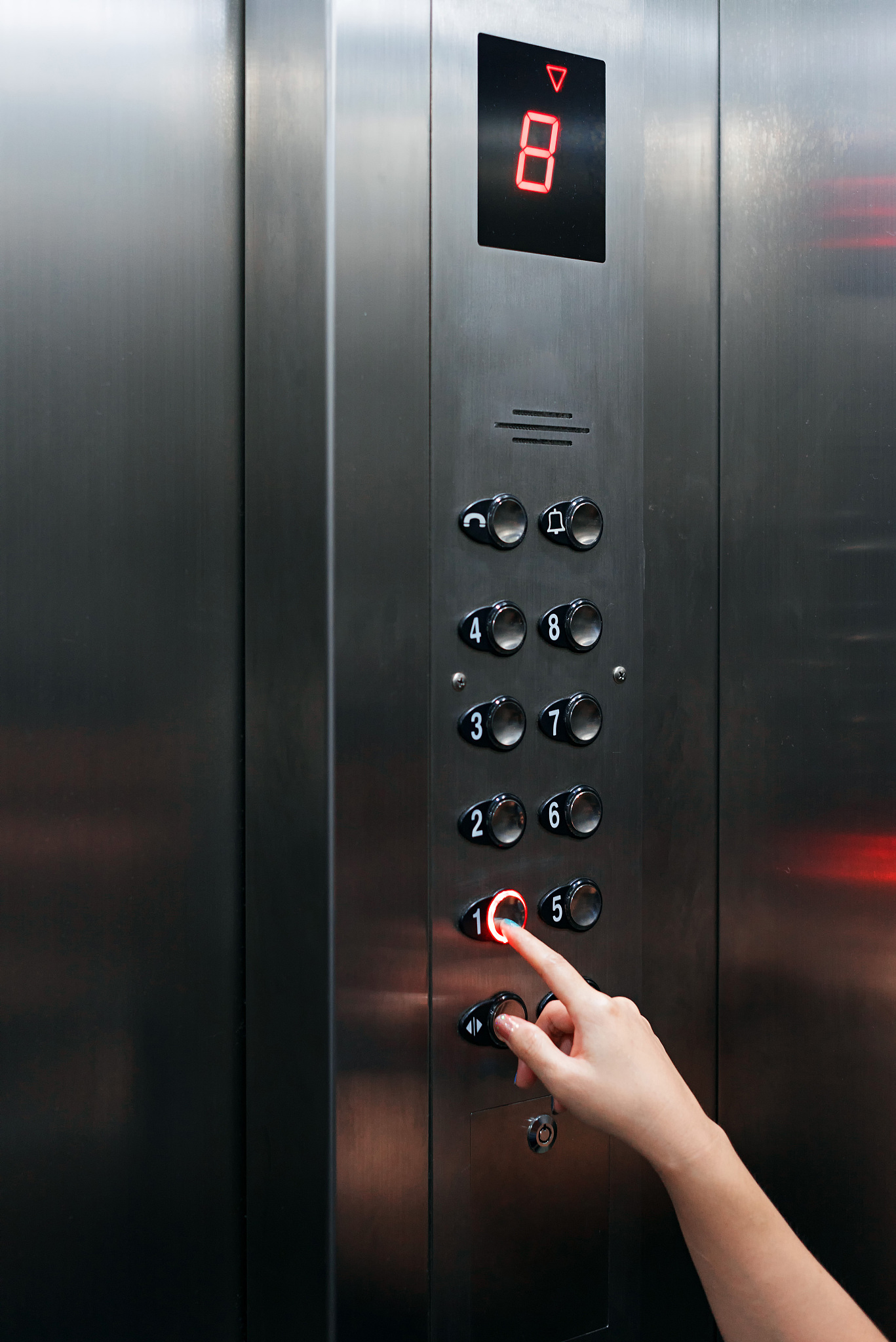 female hand pressing elevator button going downward