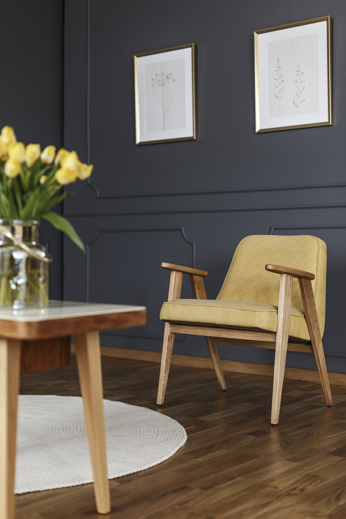 yellow wooden armchair under posters in grey living room interio