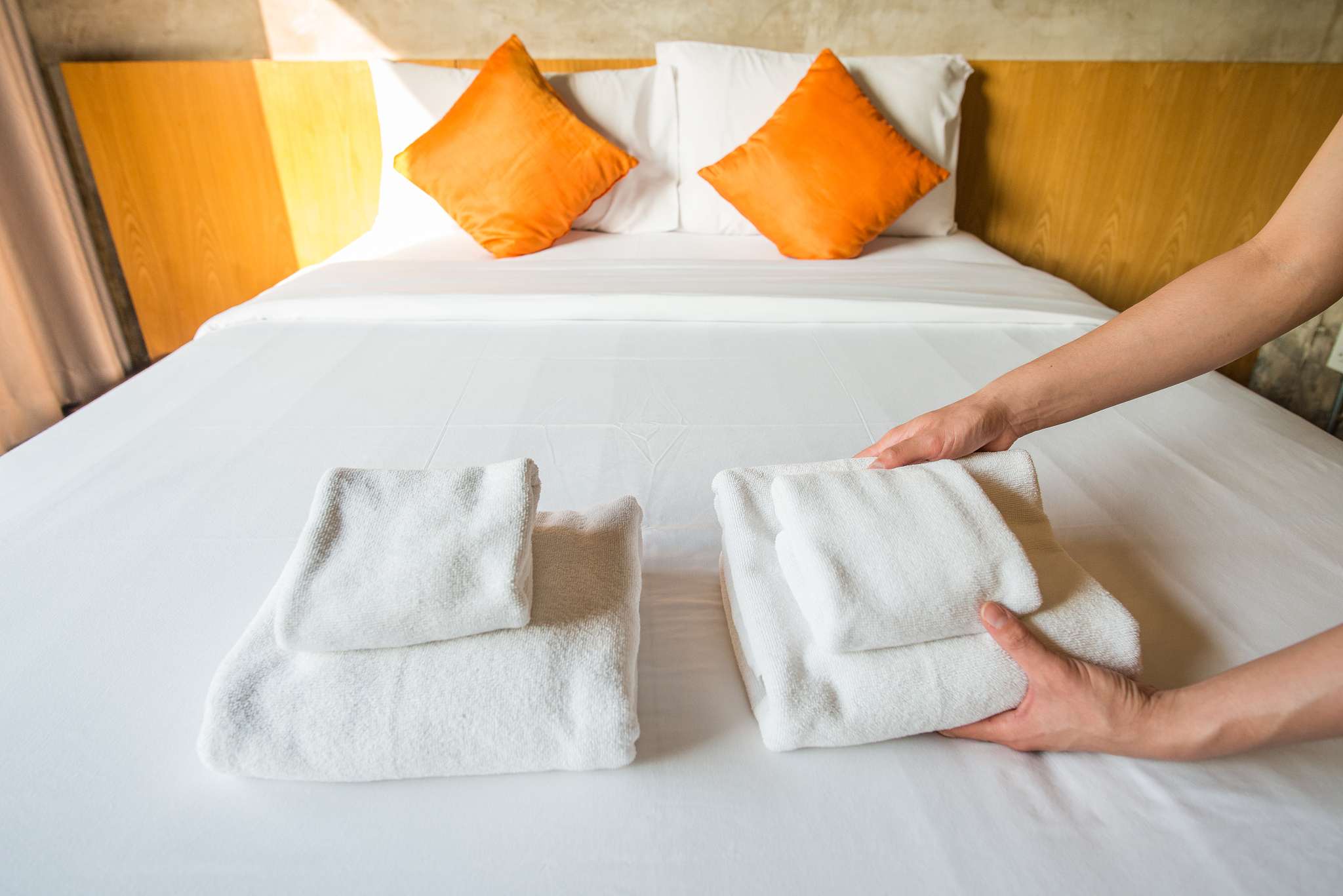 close up of hotel maid arranging the set of towels on bed.