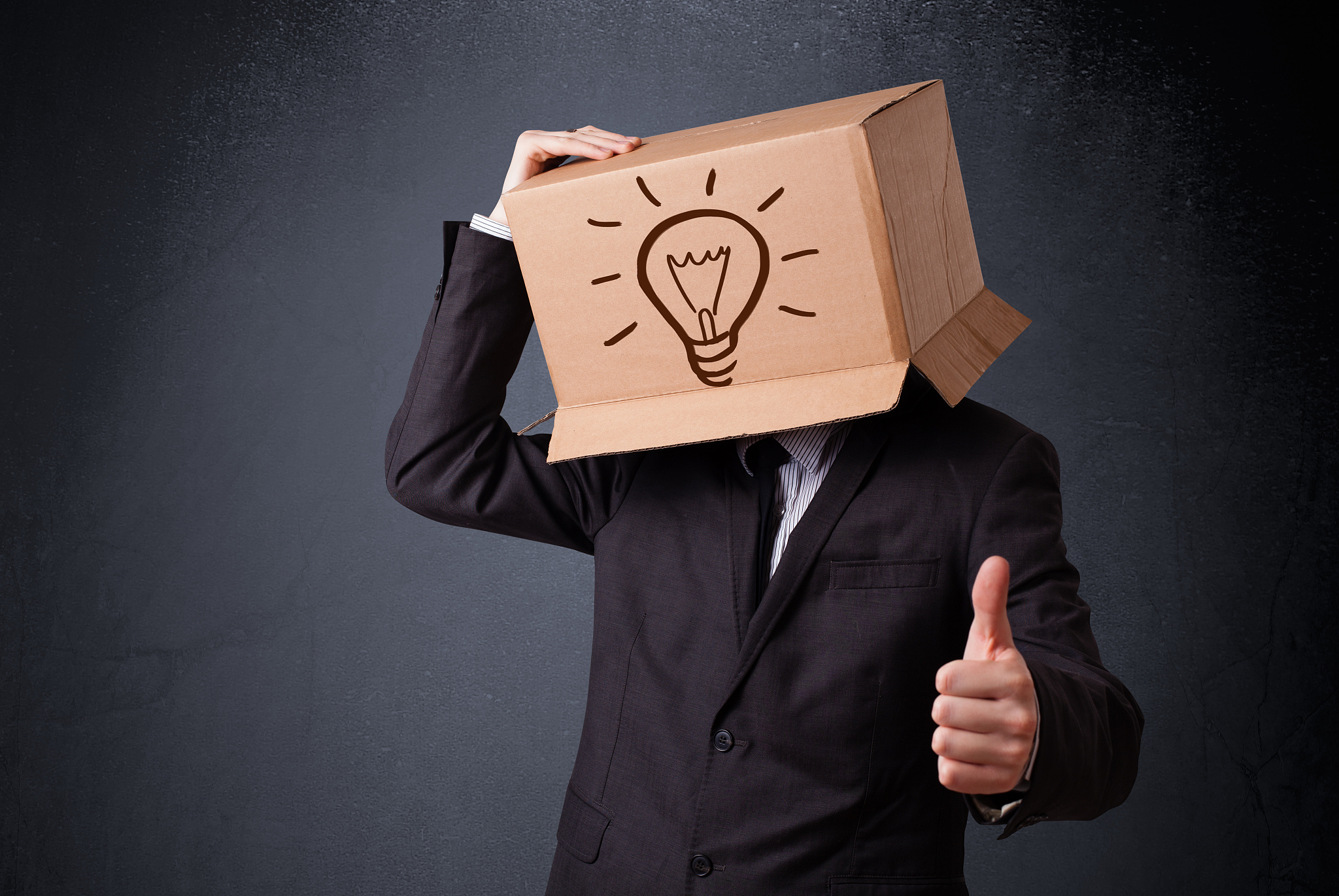 businessman gesturing with a cardboard box on his head with ligh