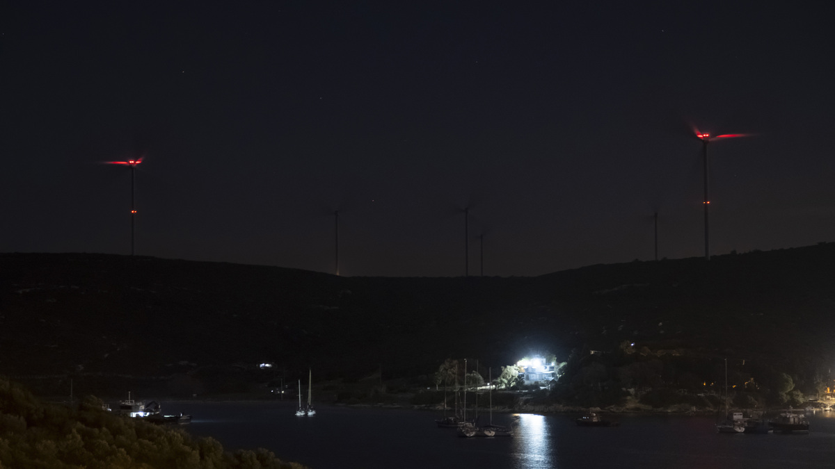 灯火辉煌的港口夜景,山丘上的风力发电机在平静的水面