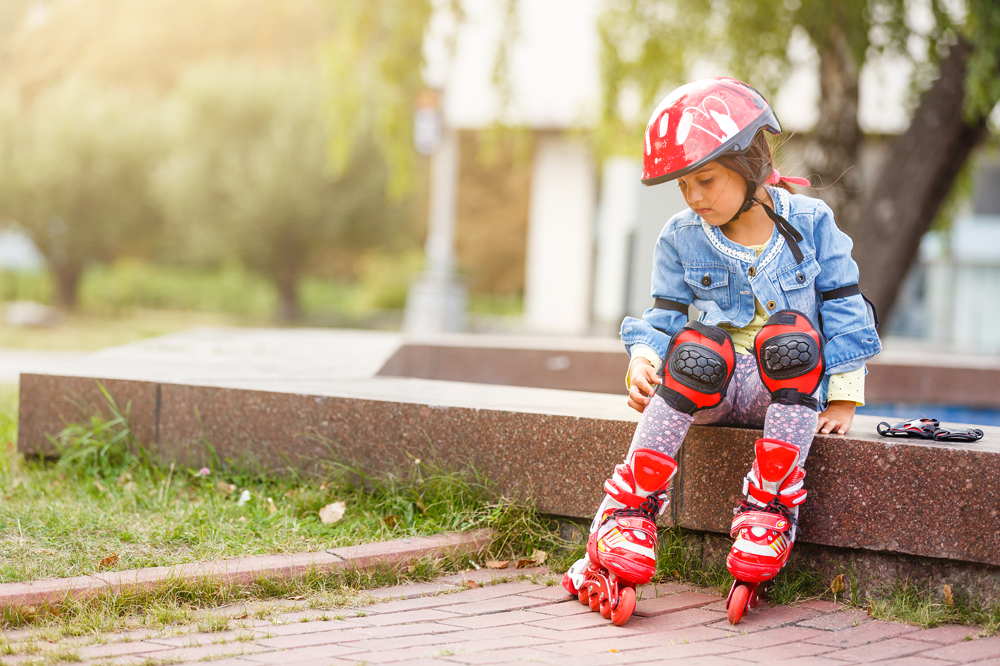 three children sitting on a park bench after rollers