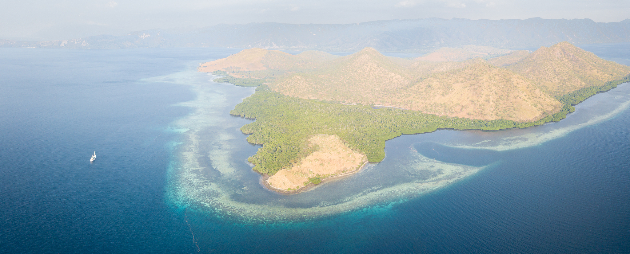 aerial view of reef, island, and ship in indonesia