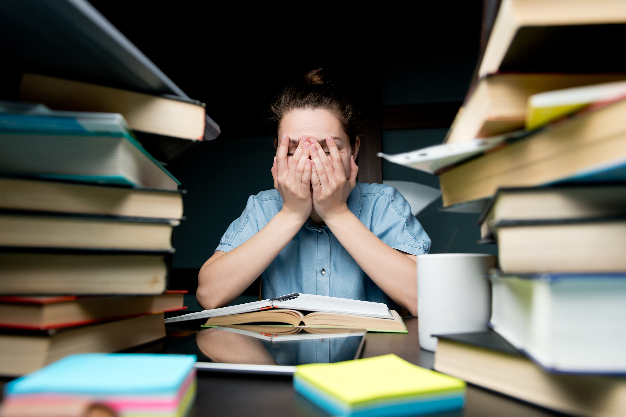 a young girl covers her face with her hands. she is tired of stu