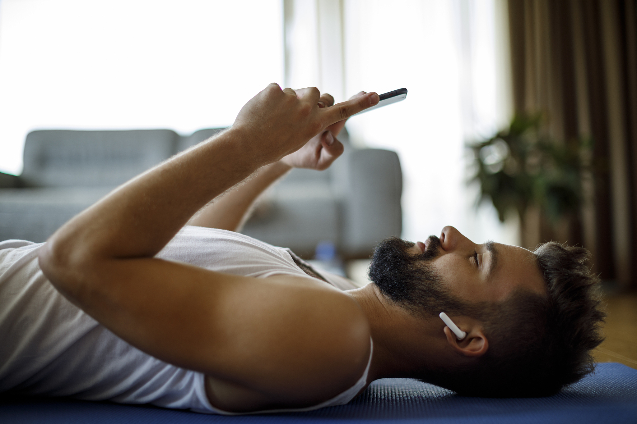 young smiling man with headphones and mobile phone relaxing afte