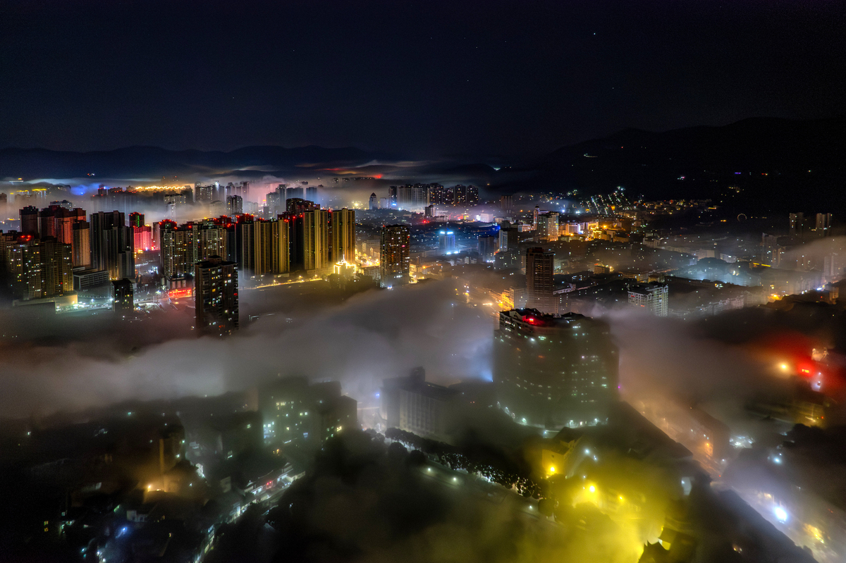 夜间雾气中城市建筑和灯光的鸟瞰图
